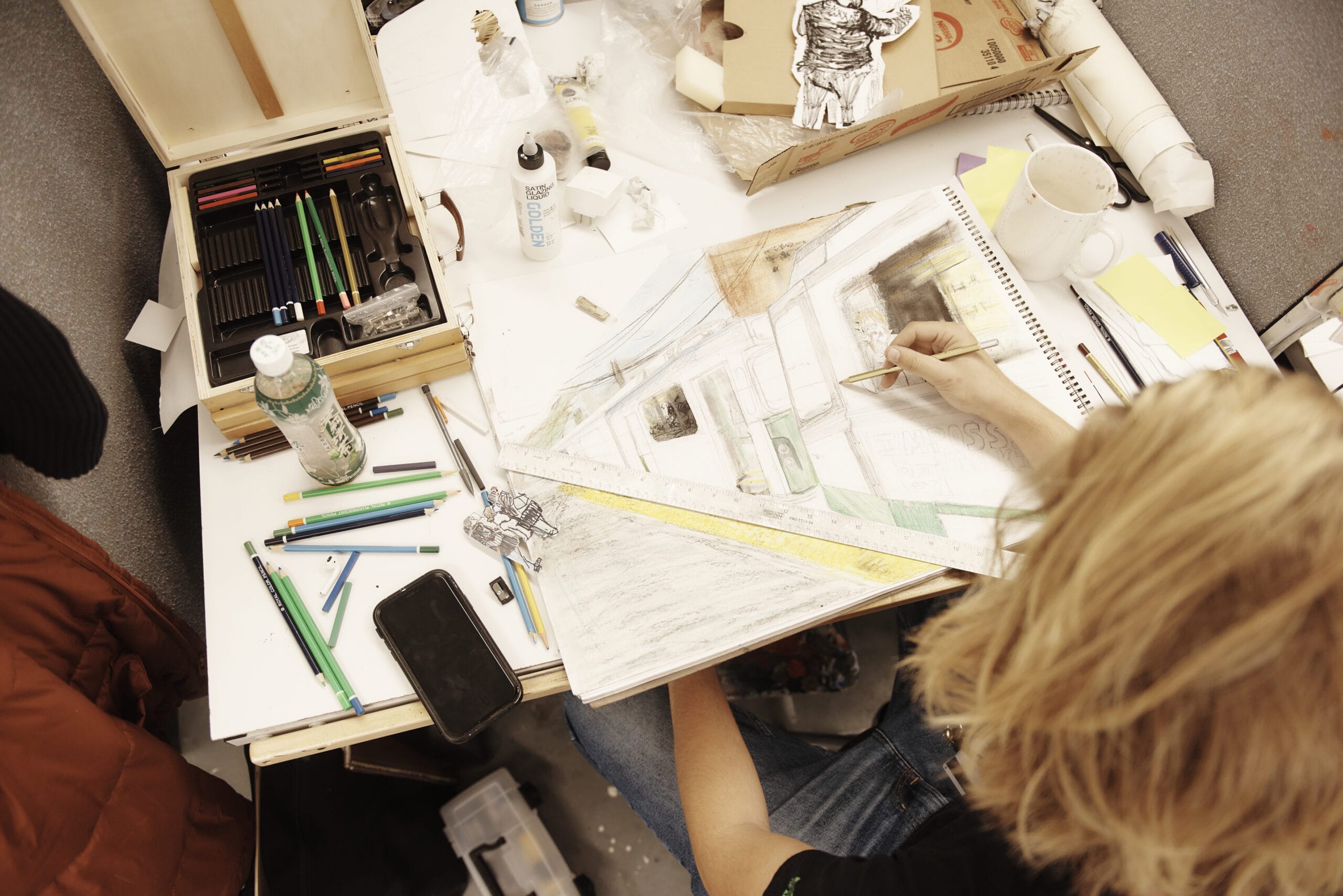A student drawing in their workspace in the Illustration studios.