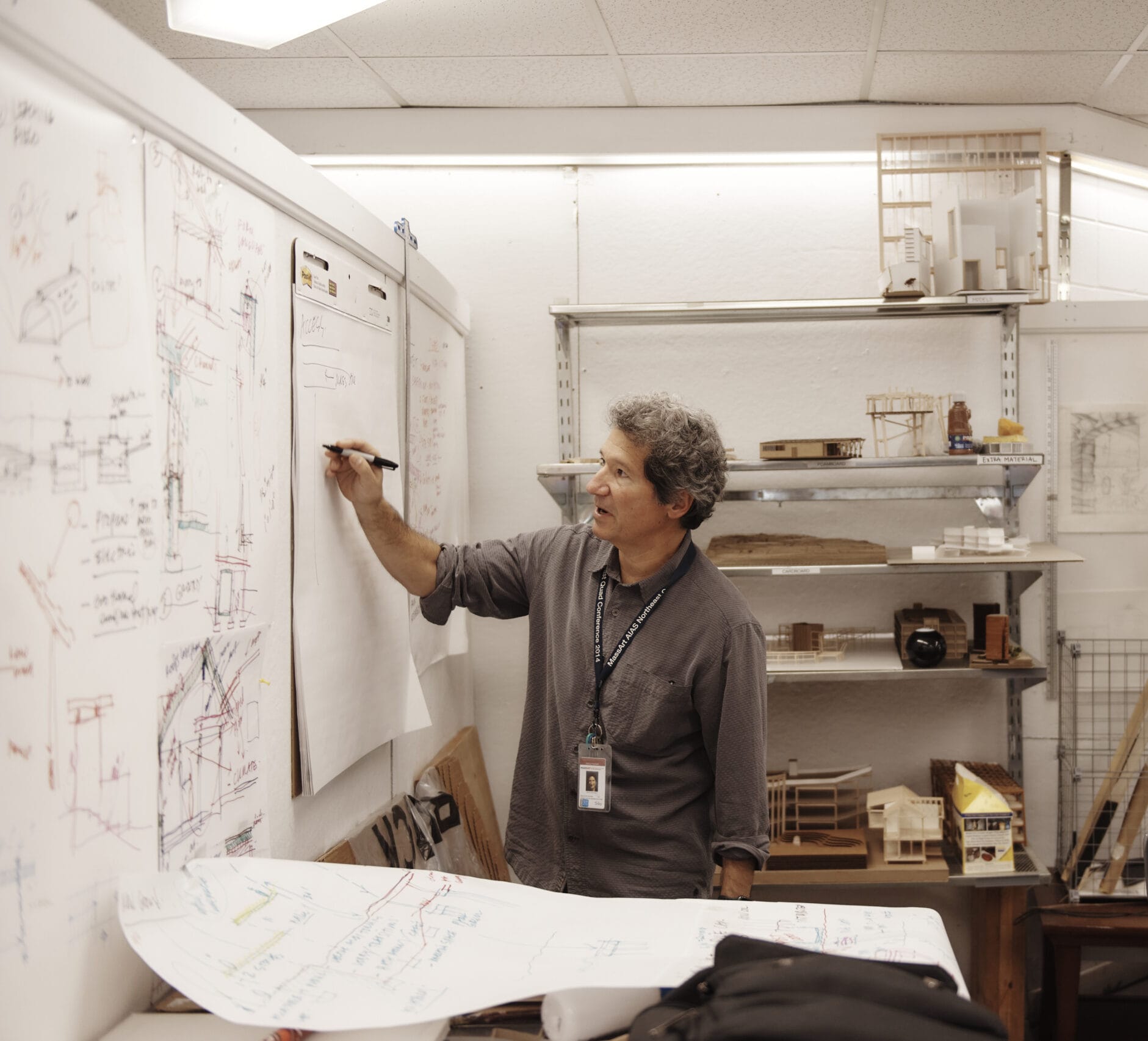 A professor stands at a white board drawing in an architecture class