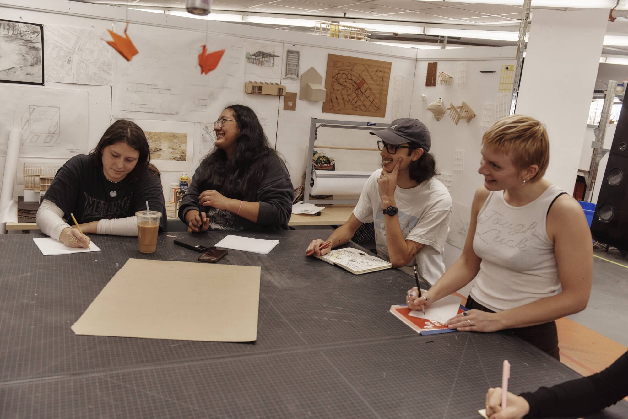 Students sit around a large work table in the architectural design studios.