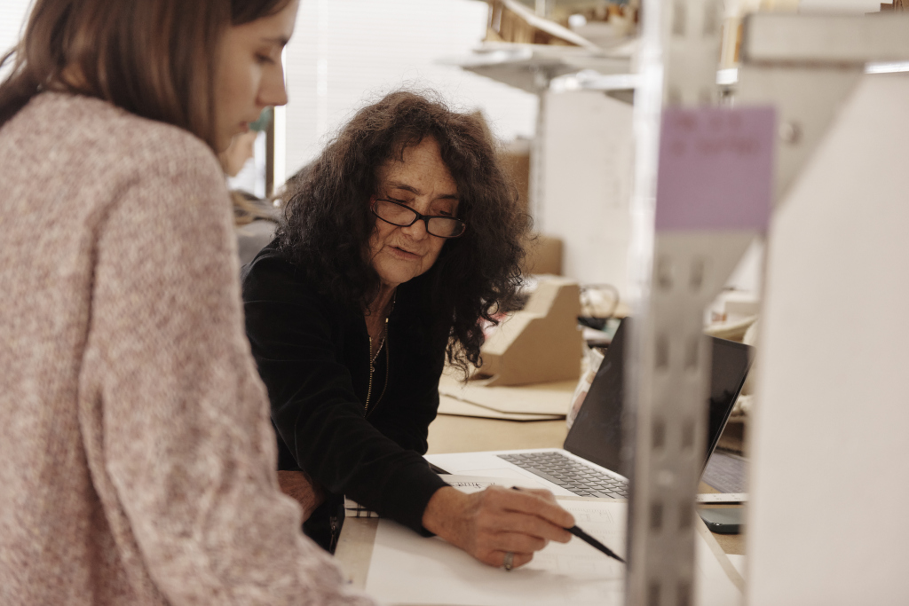 Faculty member Patti Seitz works one on one with a student at her desk.
