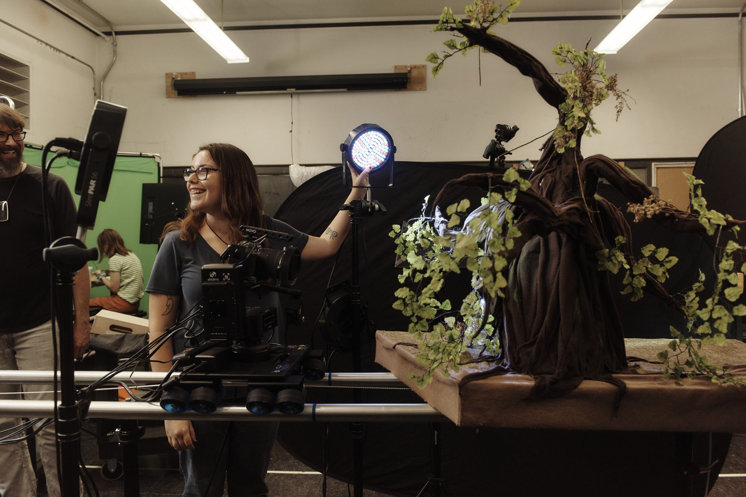 A student adjusts a light on a scene in an animation class.