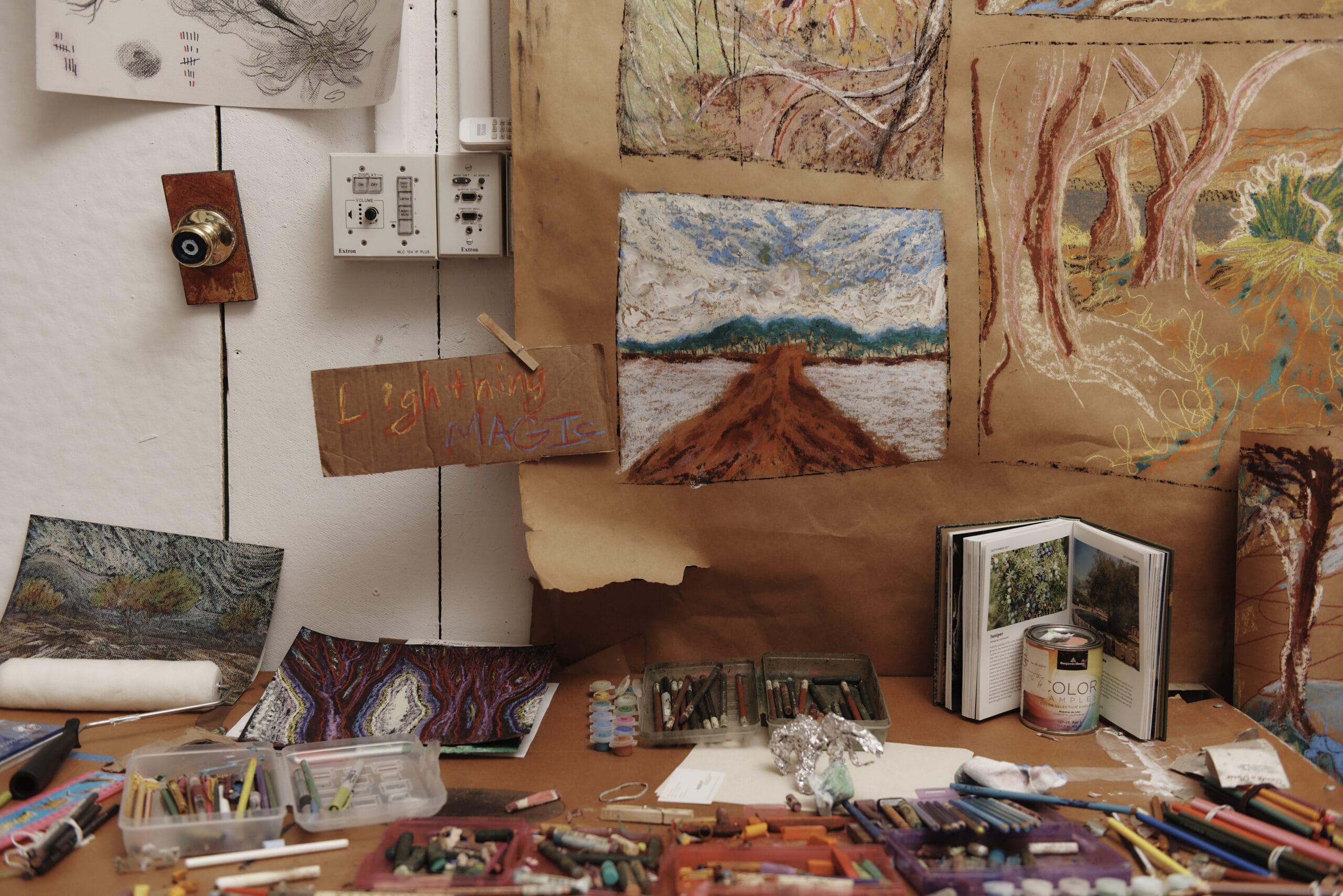 Close-up of a workspace with drawings & art supplies in the Art Education department.