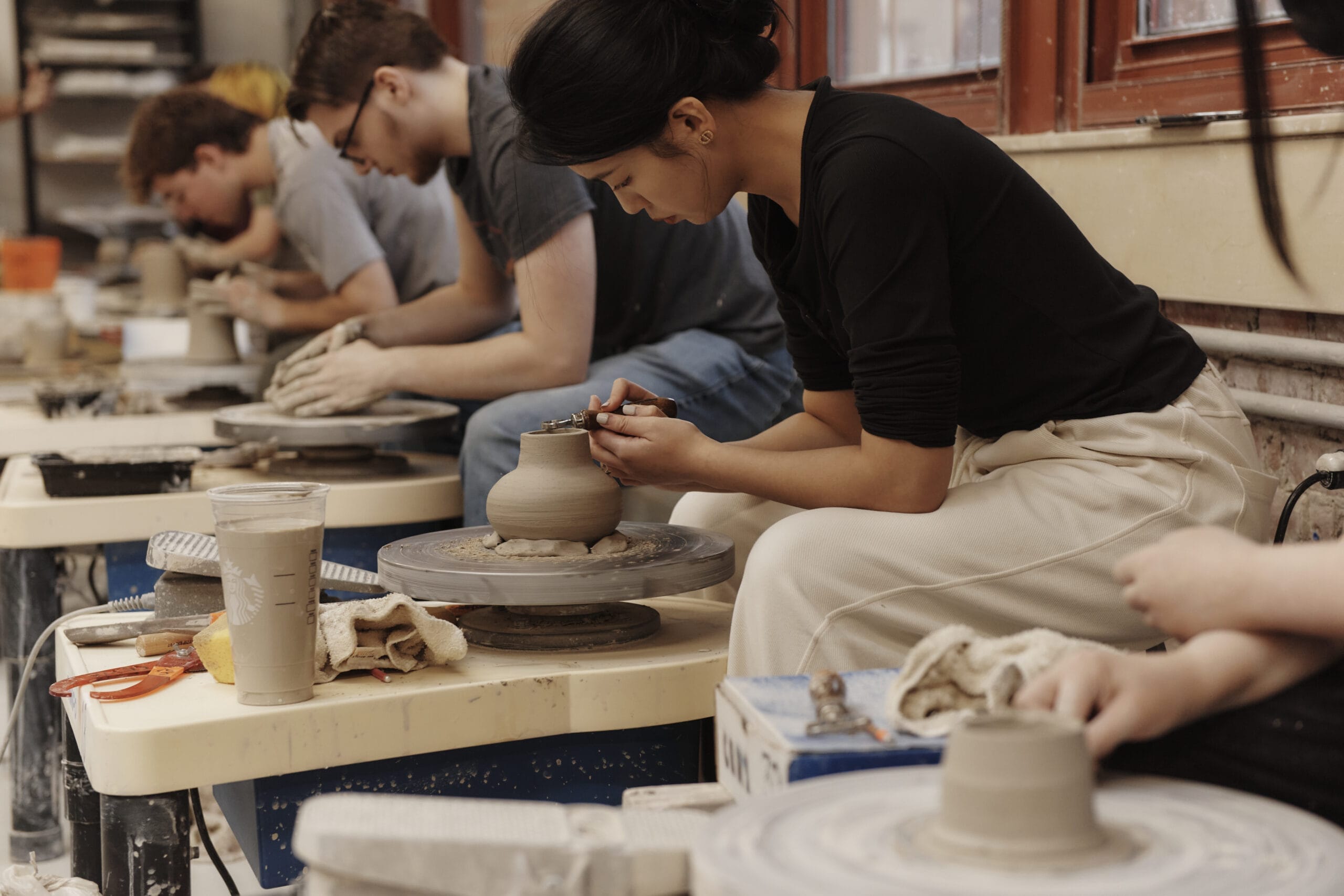 Students sit at pottery wheels