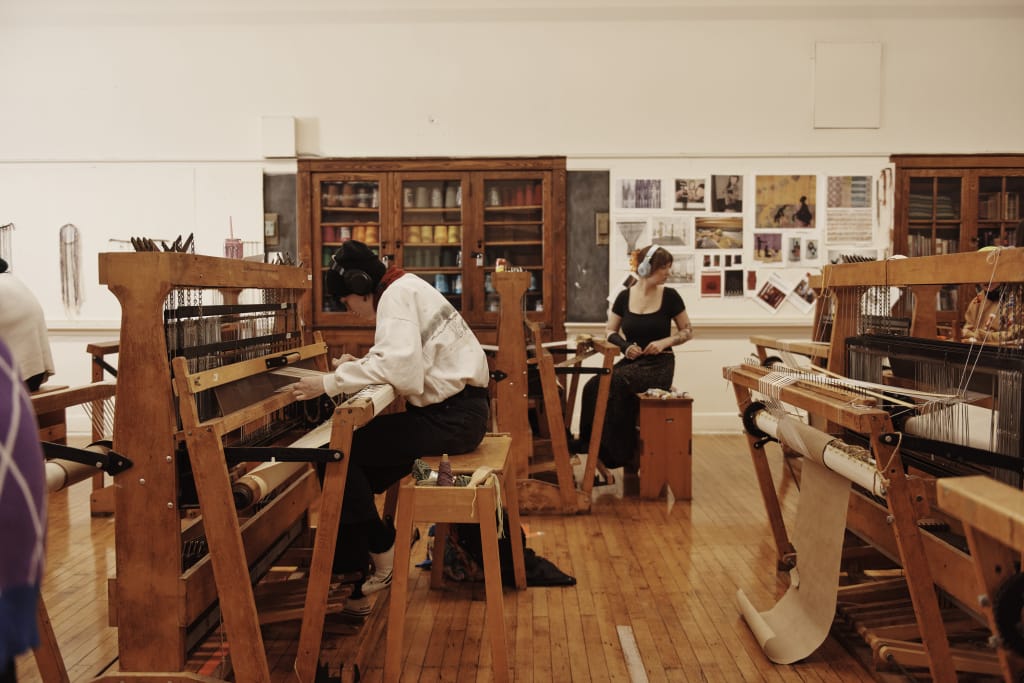 Students working on looms, weaving