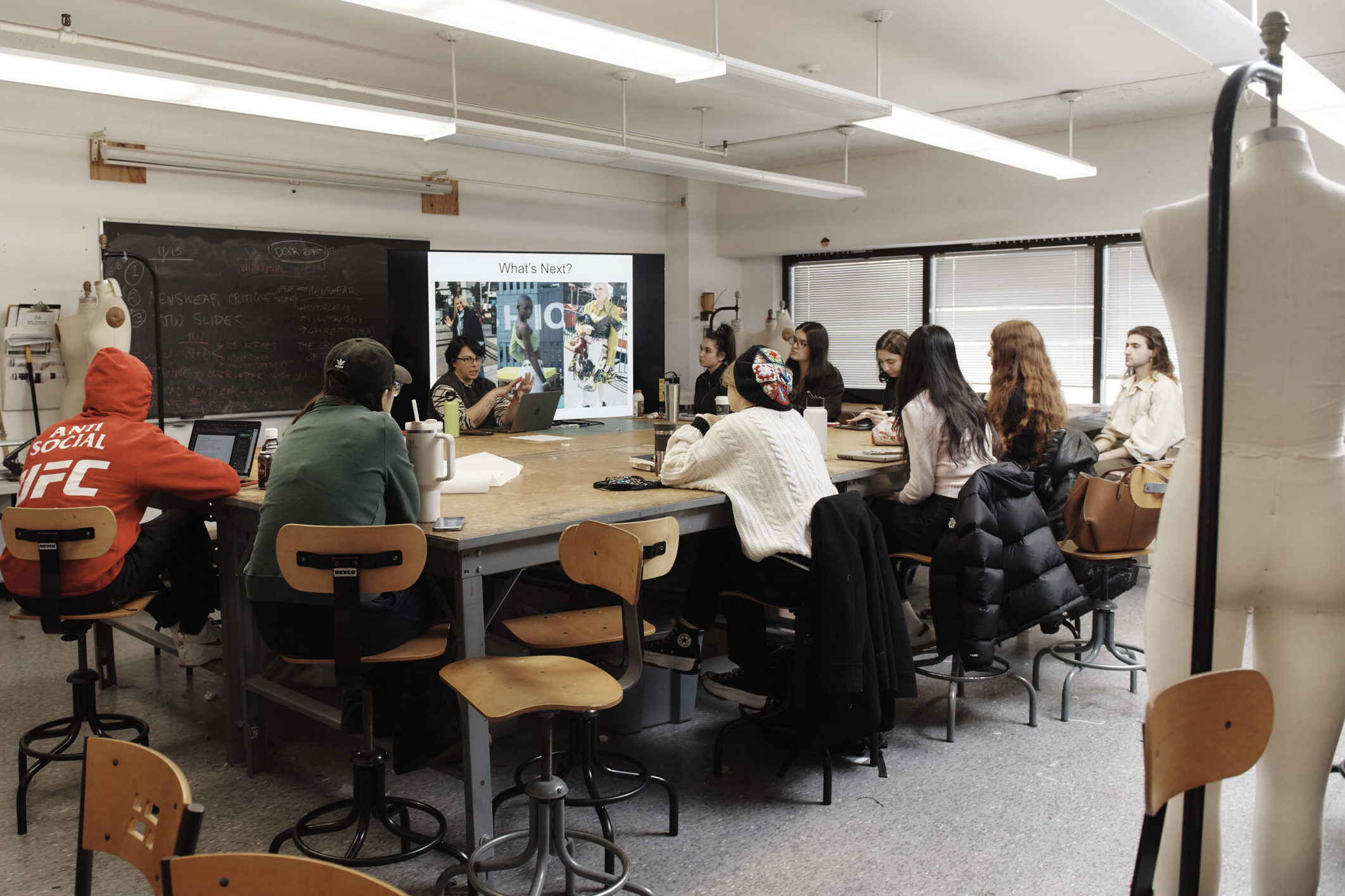 Students sitting at a large communal table in the Fashion Design department.