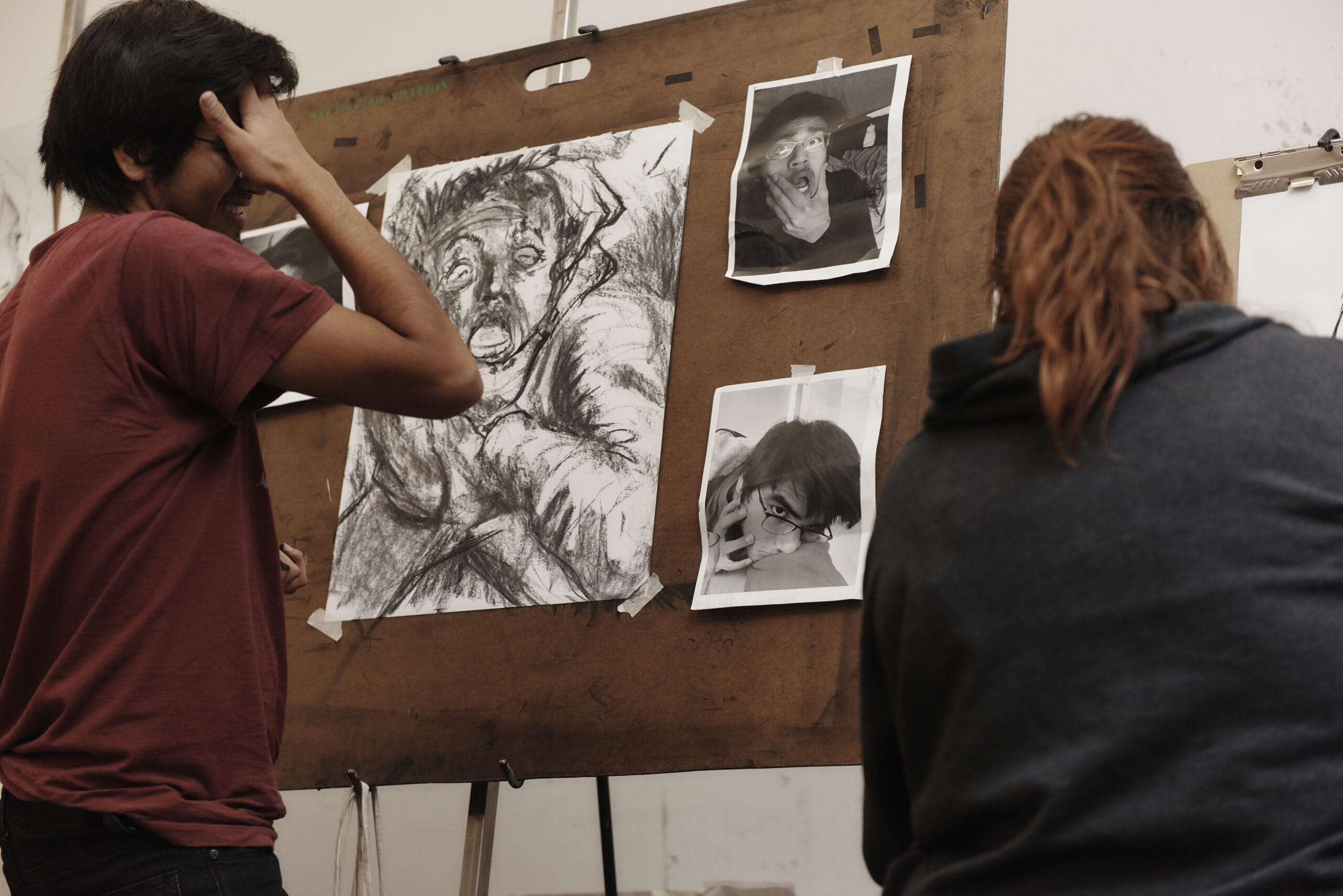 Two students in front of a charcoal painting