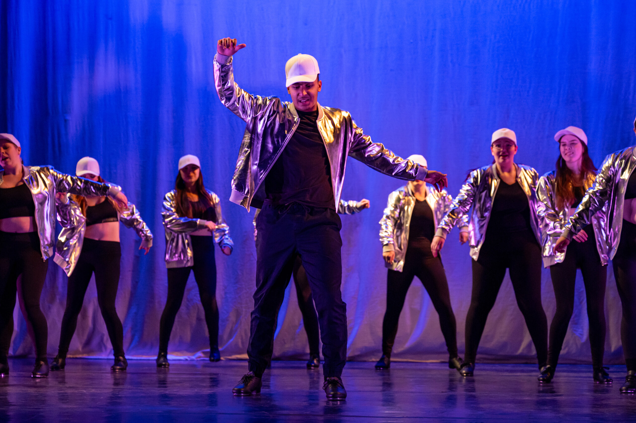 Hip hop dancers dance on a stage in black and gold outfits