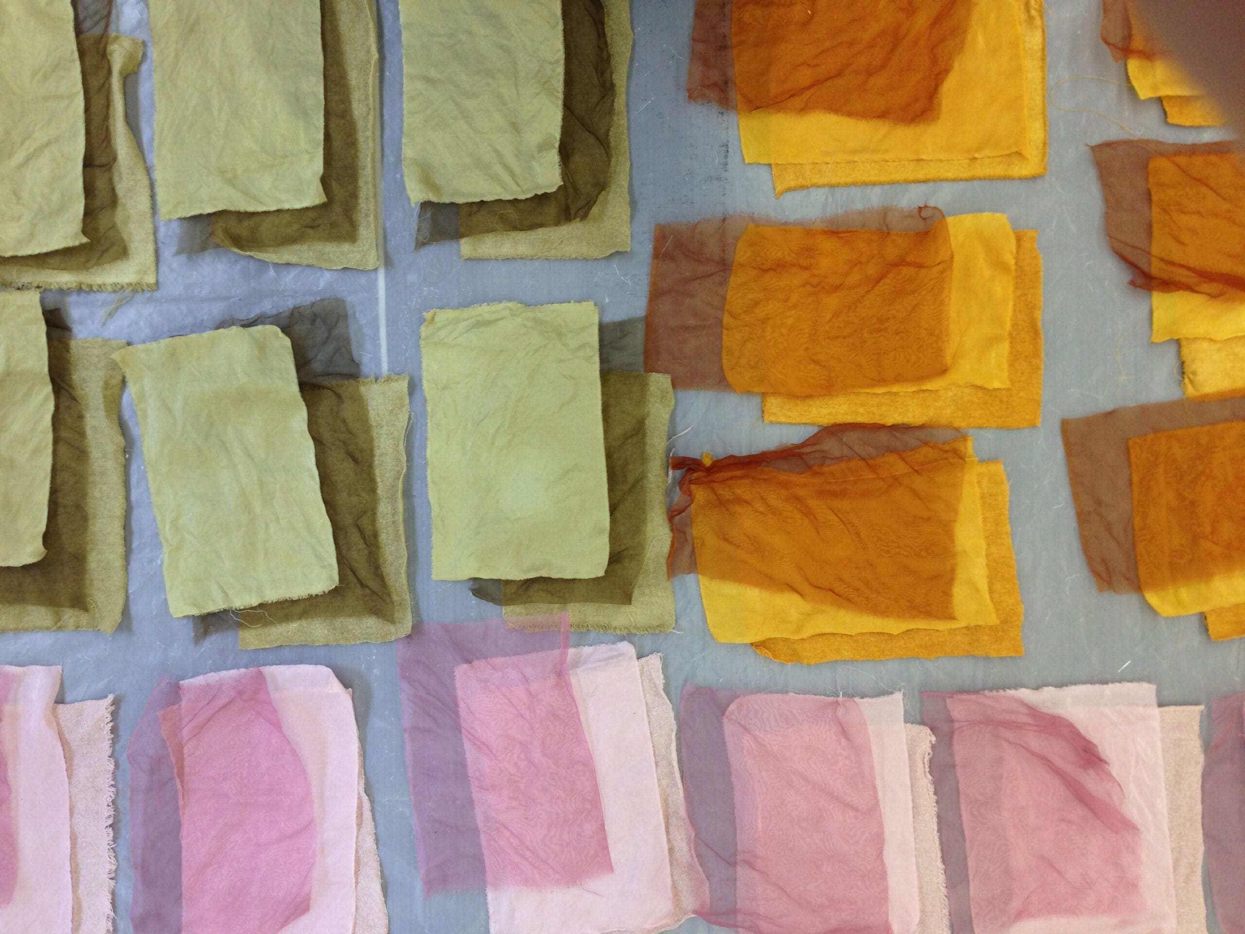 Rectangles of different types of fabric stacked on top of one another in green, orange, and pink.