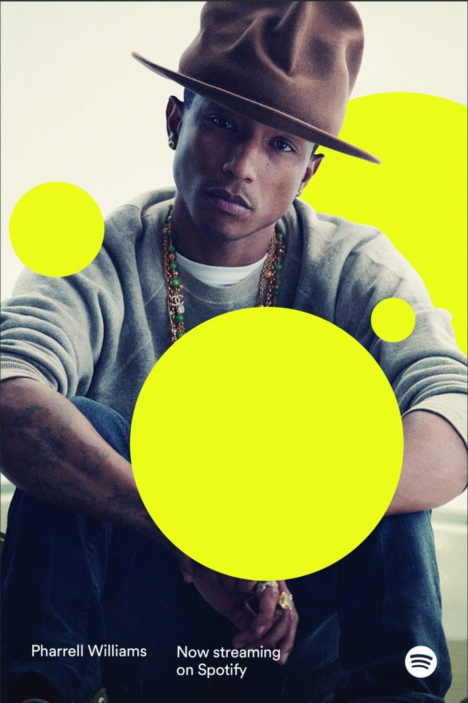 A person wearing a large brown hat and a gray sweater sits with their arms crossed. Bright yellow circles overlay the image. Text reads: Pharrell Williams Now streaming on Spotify with Spotifys logo in the corner, seamlessly integrated into their distinct identity system.