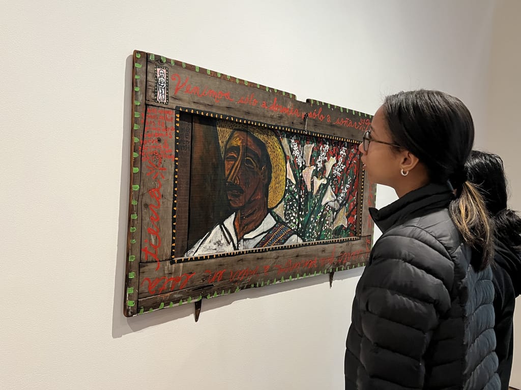 Photo of a MassArt students observing artwork at MAAM.