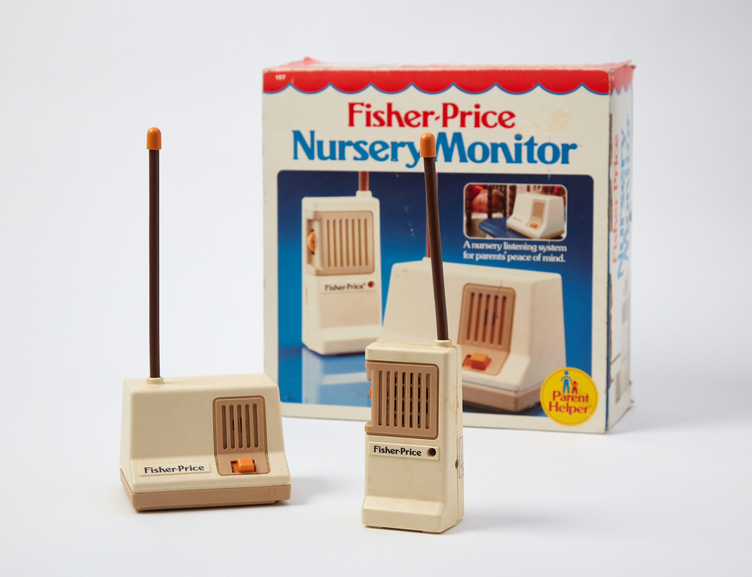 Two vintage Fisher-Price nursery monitors with long antennas and beige bodies are displayed. Incorporating elements of human design, one features an orange switch. Behind them, the packaging shows a child sleeping, emphasizing a nursery listening system for motherhoods peace of mind.