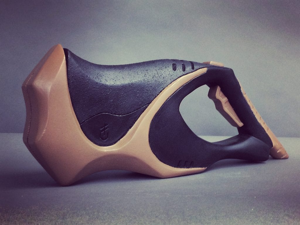 A modern, stylized hammer with a unique design lies beside a reciprocating power saw. The handle is sleek and black, while the striking surfaces are a contrasting tan. Both tools boast ergonomic curves and a minimalist aesthetic, perfect for any contemporary toolbox.