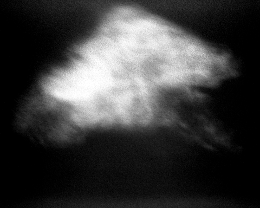 An abstract black and white image reminiscent of The Witching Hour, resembling a cloud or smoke against a dark background. Its soft edges and varying shades of gray evoke an enigmatic sense of movement and fluidity, as if the night itself were whispering secrets.