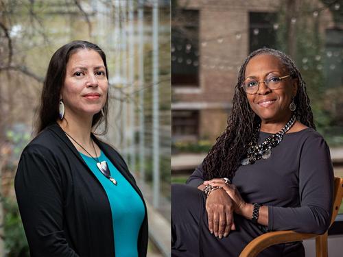 Two women are posing outdoors. On the left, Elizabeth James-Perry sports long dark hair, a black jacket, and a turquoise top. Seated on the right is Ekua Holmes with braided hair and glasses, dressed in dark attire and smiling with her hand on her chin.