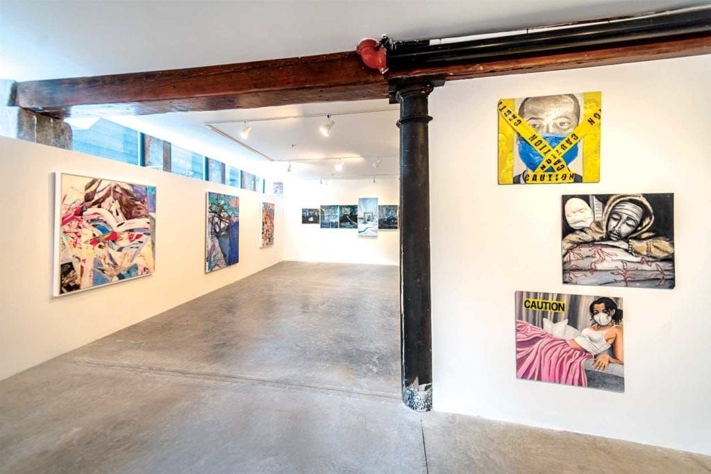 The New Gallery in the South End boasts white walls adorned with vibrant artworks, including abstract designs and a woman in a mask with caution tape. This modern art space features concrete floors and industrial elements like exposed beams and pipes.