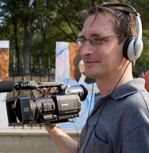 Steve Gentile holding a video camera wearing headphones.
