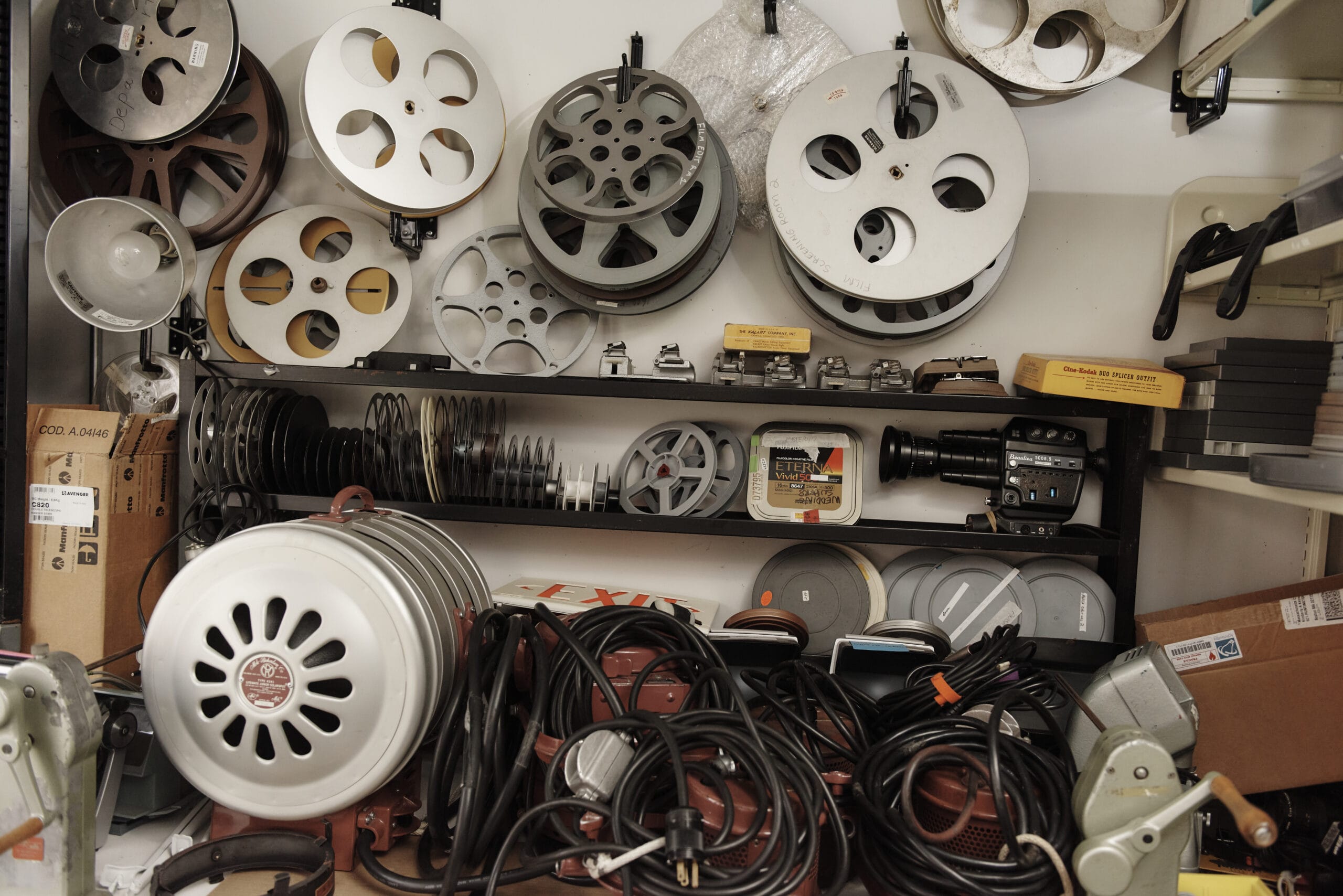 An equipment area with film spools hanging on the wall and cords wrapped up piled below.