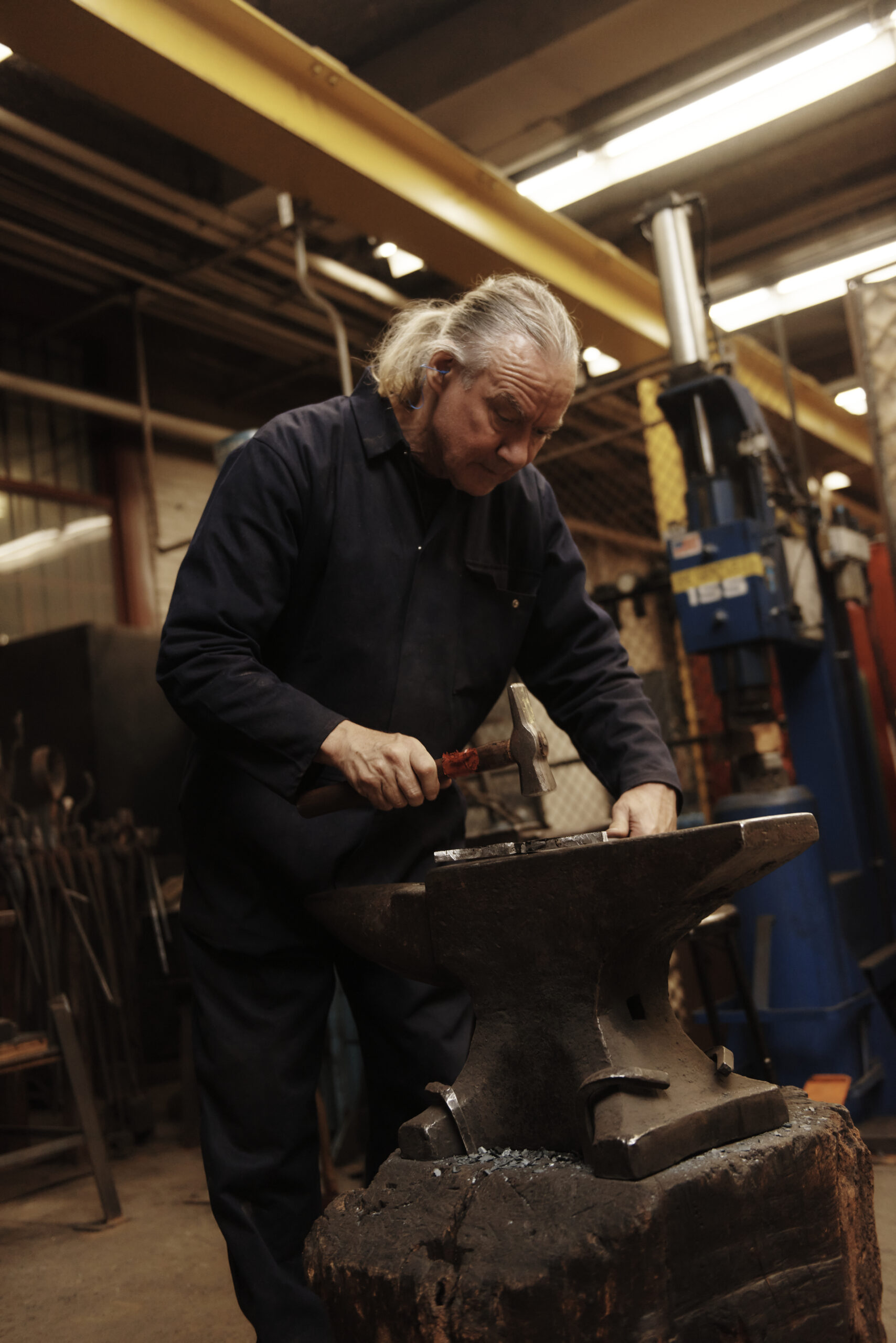 Student using a metal hammer to shape metal on an anvil