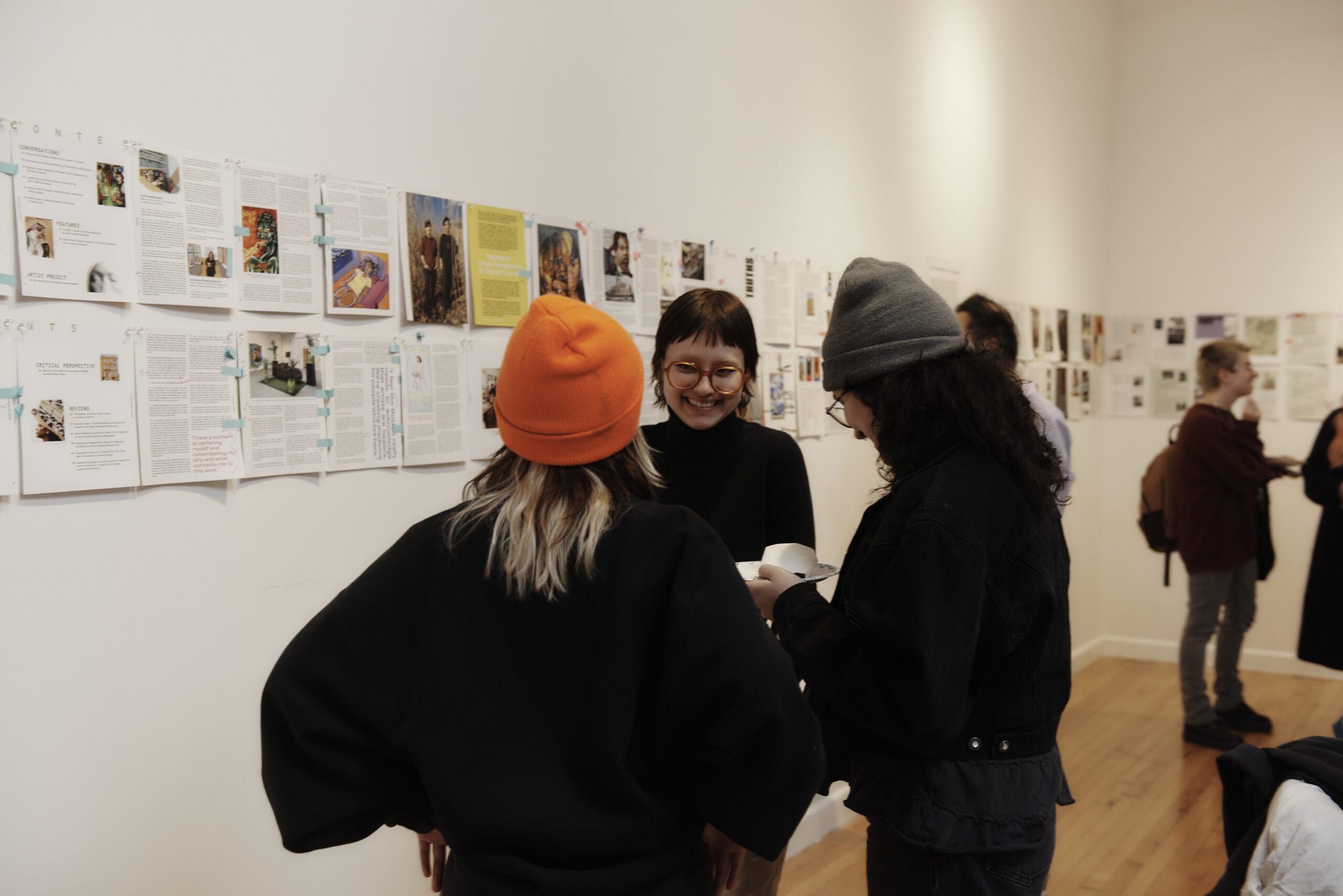 Students stand together talking in a gallery.