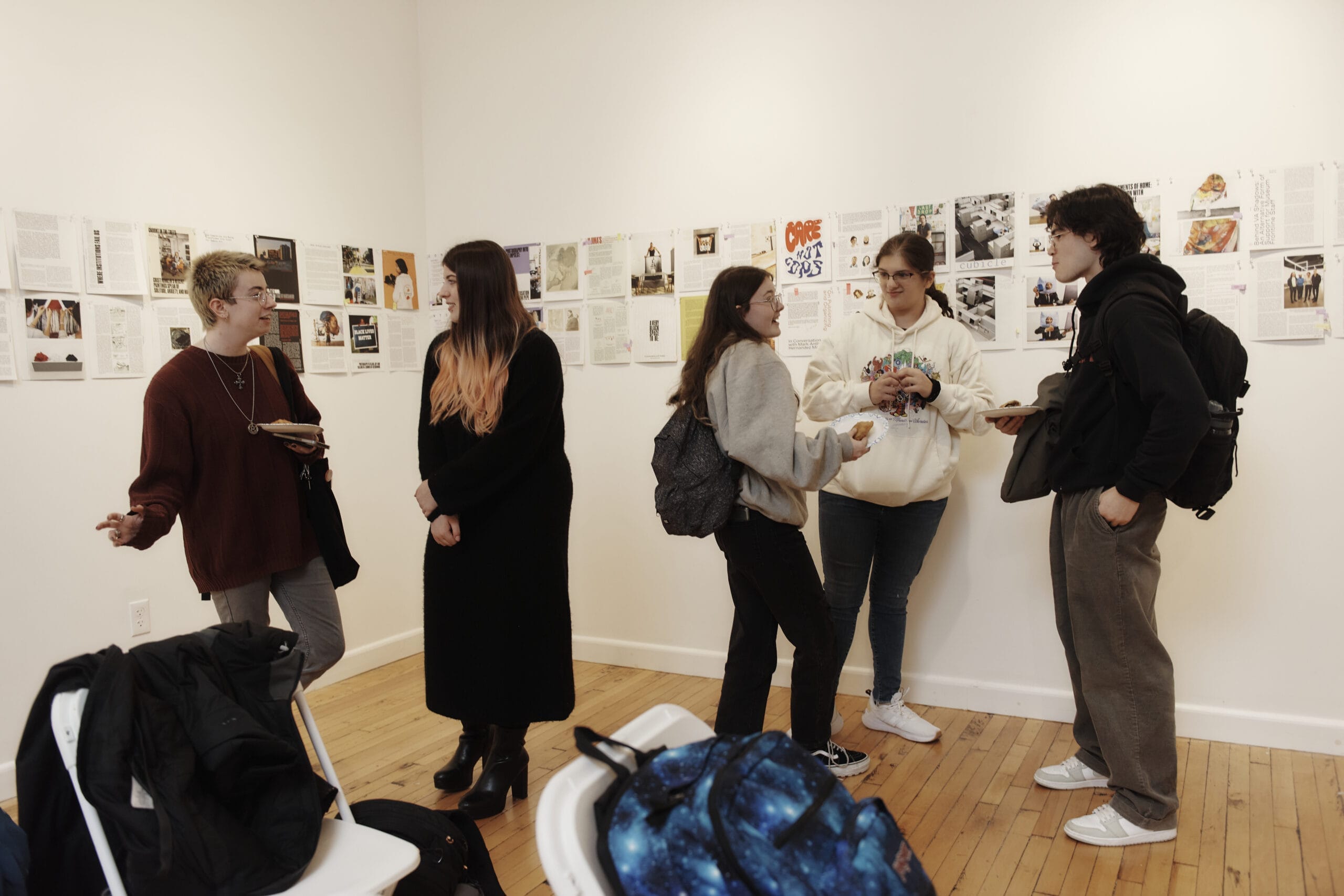 Students stand around chatting in a gallery.