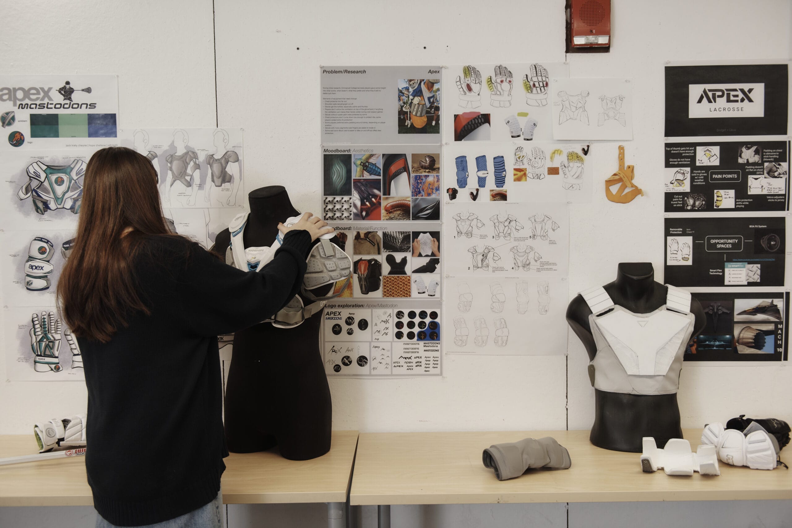 An industrial design student adjusts her product work on display.