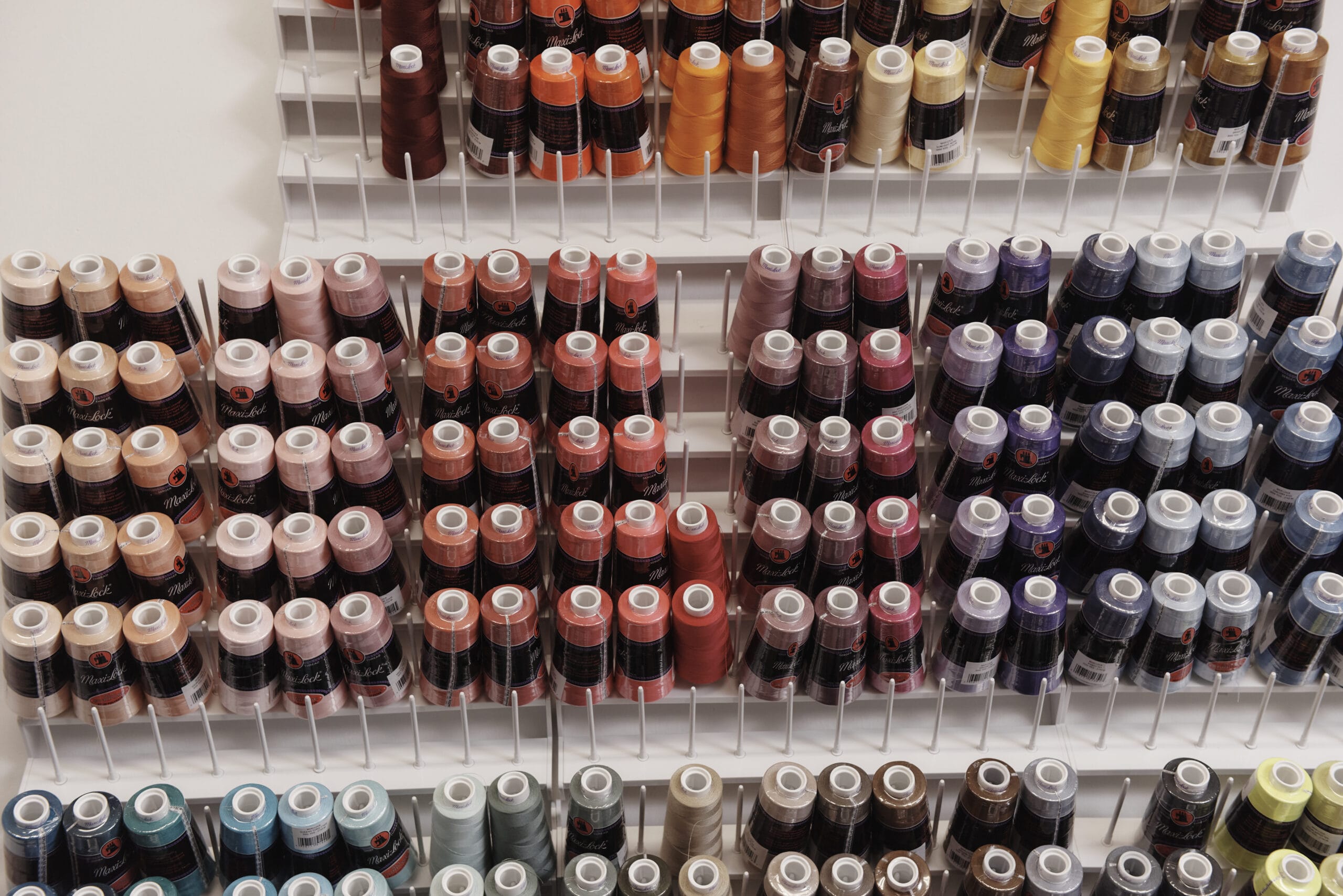 A wall of organized thread spools, arranged by color.