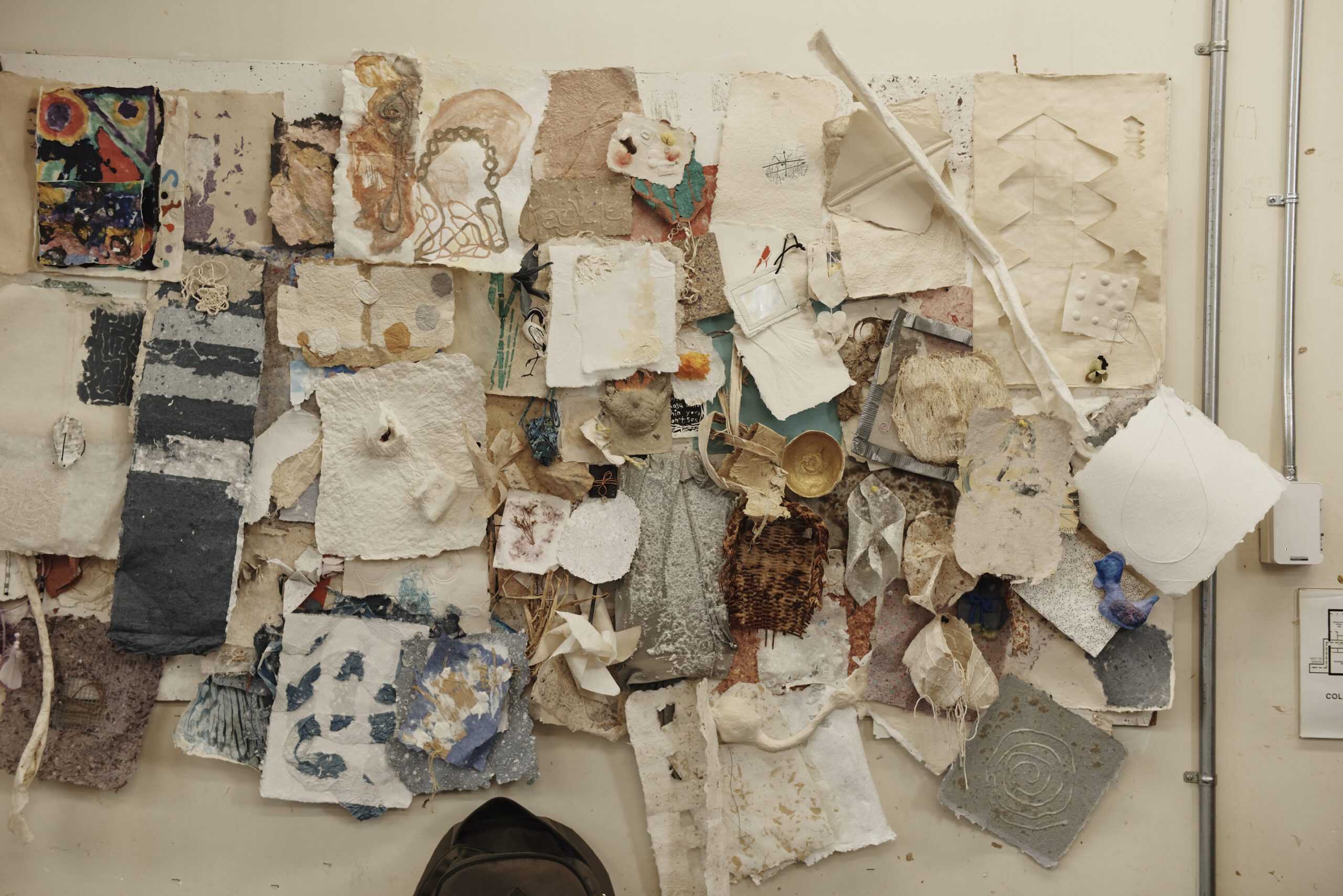 Handmade paper samples hung up on the wall in PaperMaking class.