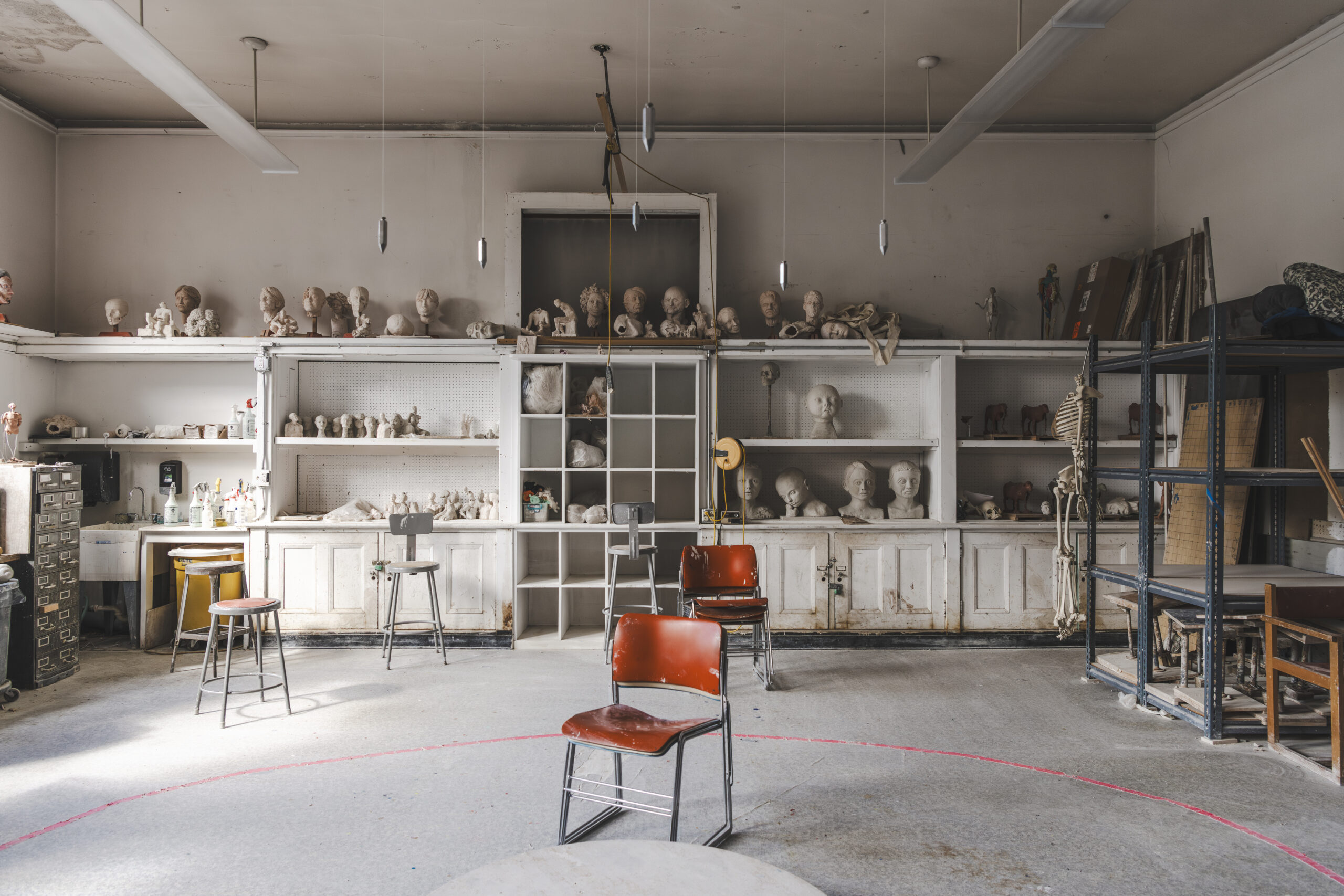 Sculptures lined up on a large built-in cabinet in a white classroom