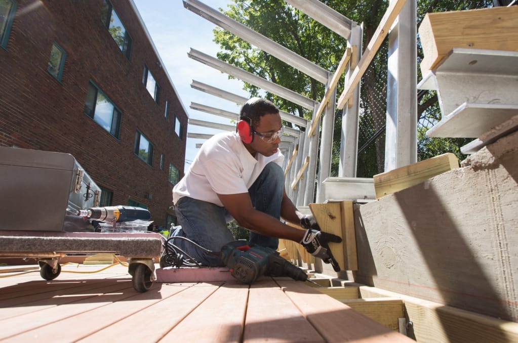 A Grad student works on building an outdoor structure at Codman Academy
