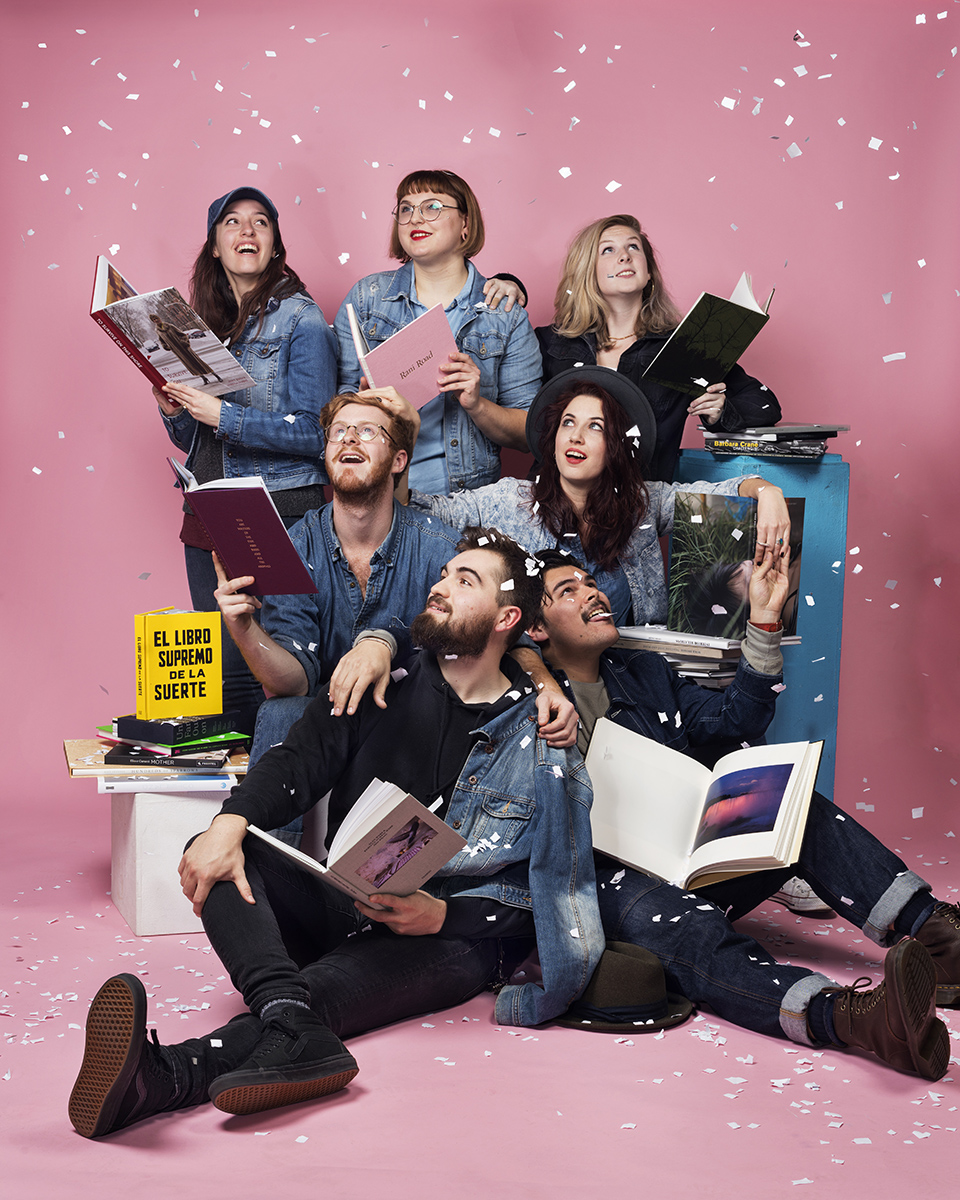 Students holding books on a bright pink background