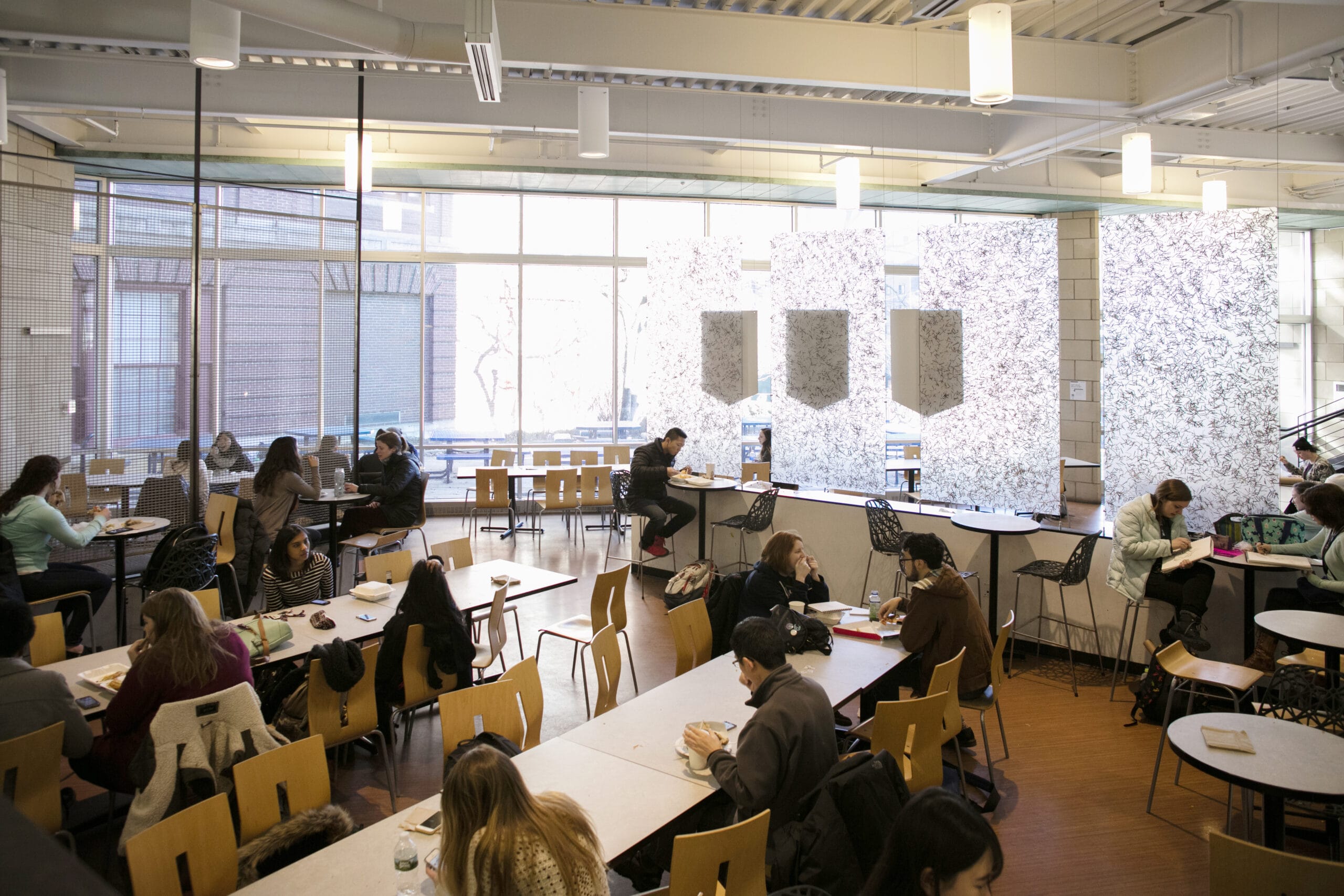 Students sit at tables eating in a modern dining hall.