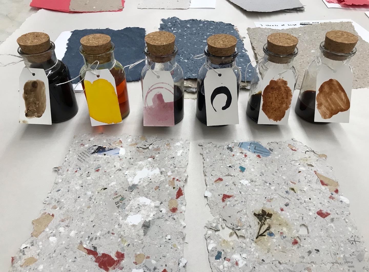 Ink bottles with handmade paper, laid out on a table.