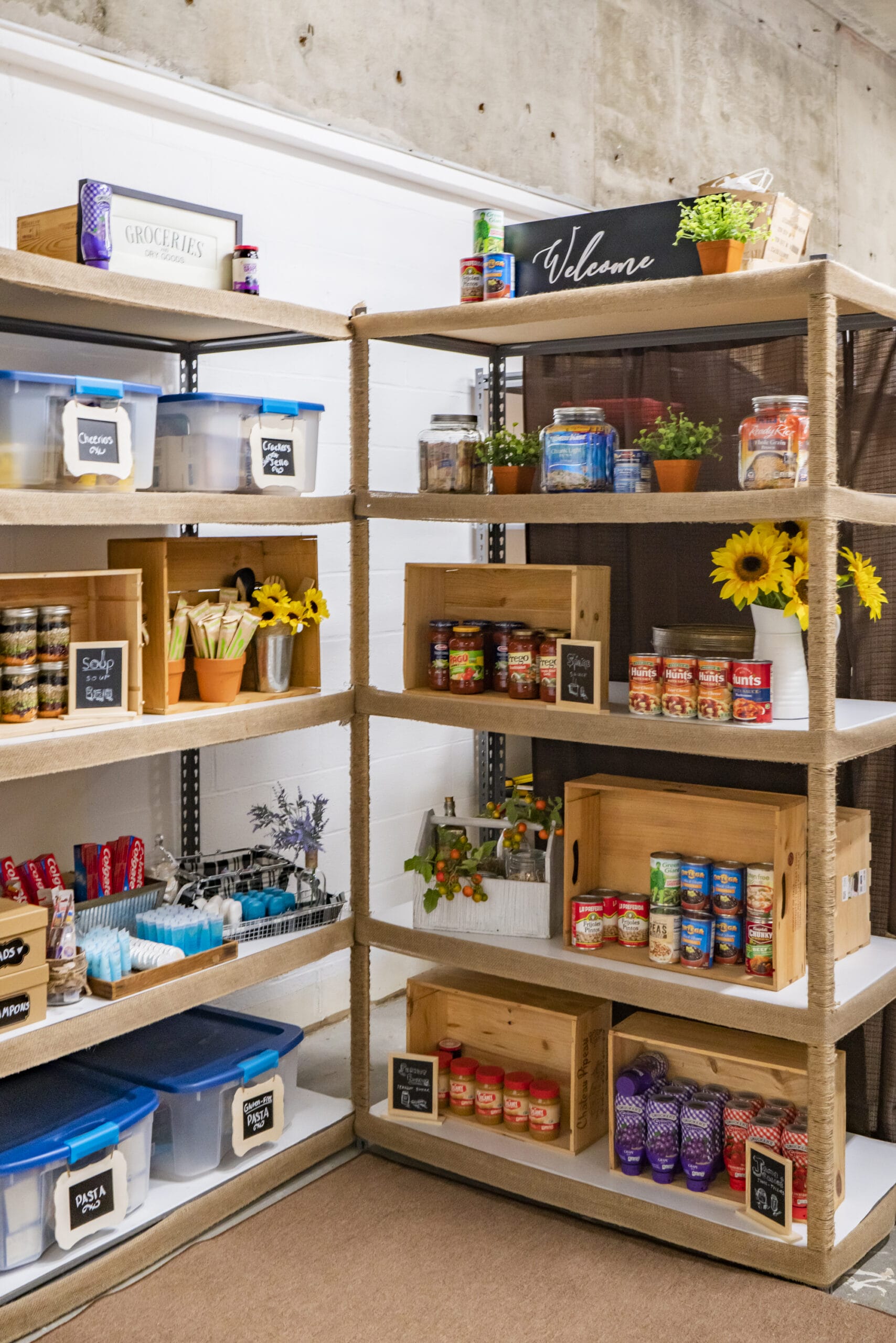 A brightly lit room with shelves of non-perishable foods and hygiene supplies.