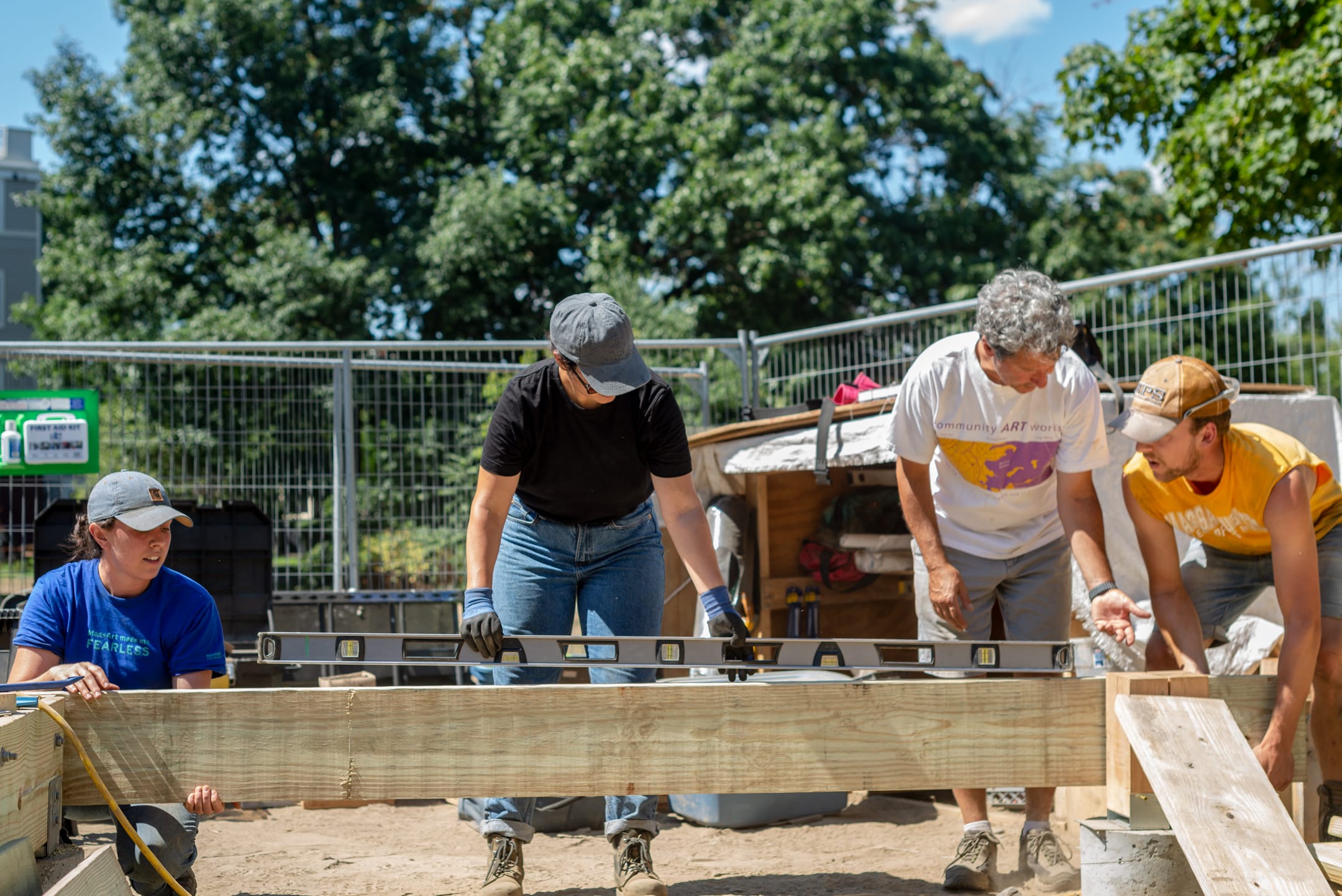 People stand outside around a building foundation with a level.