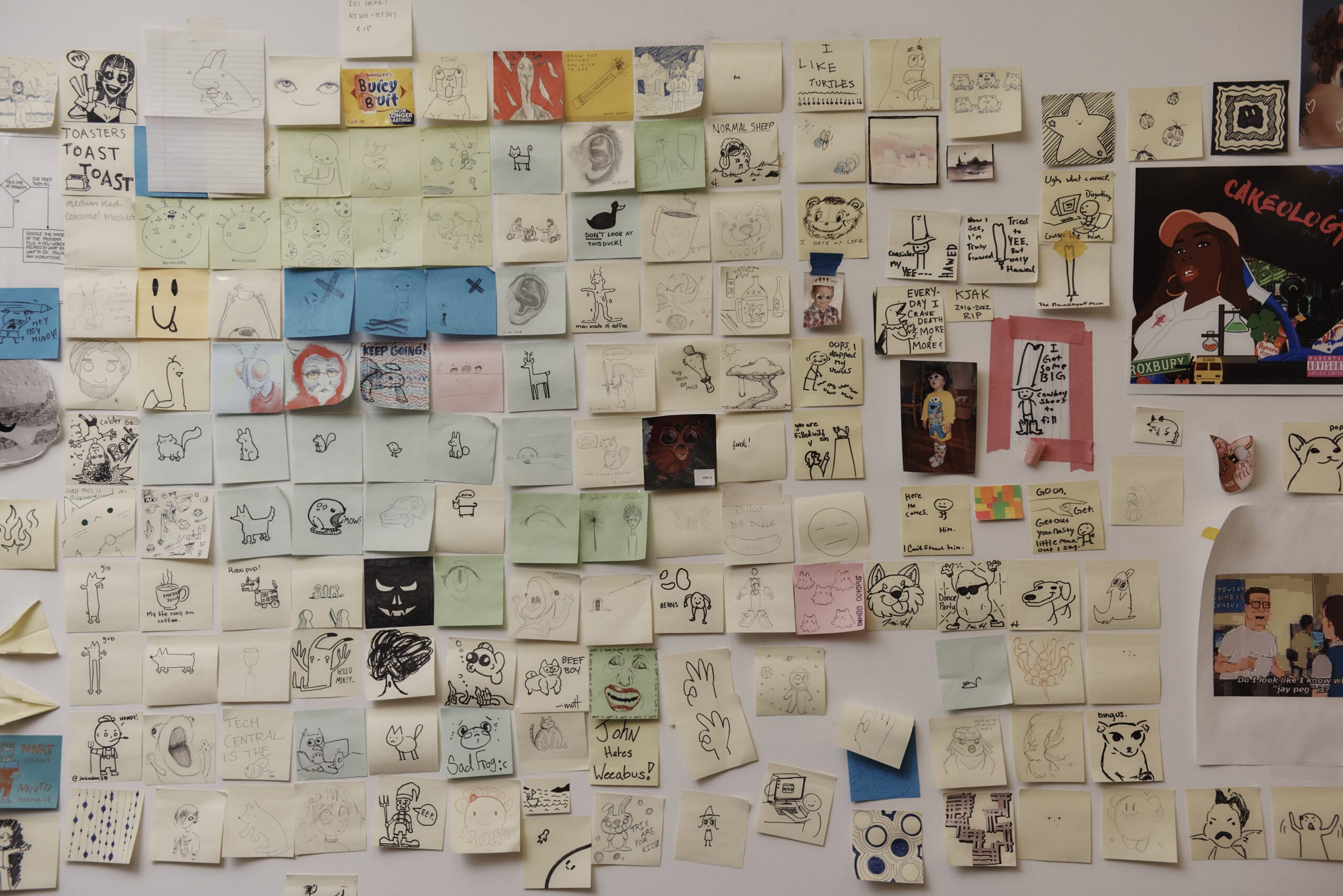 A wall covered in mult-colored post-it notes with drawings and writing on them.