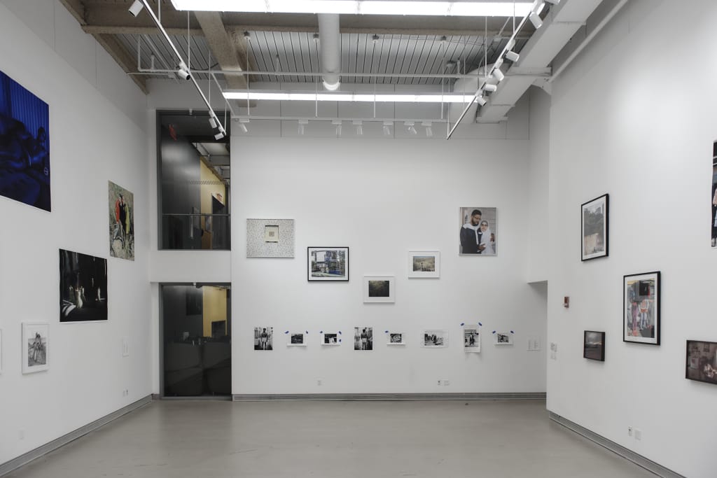 A large 2-story white gallery space with photography shown on the walls.
