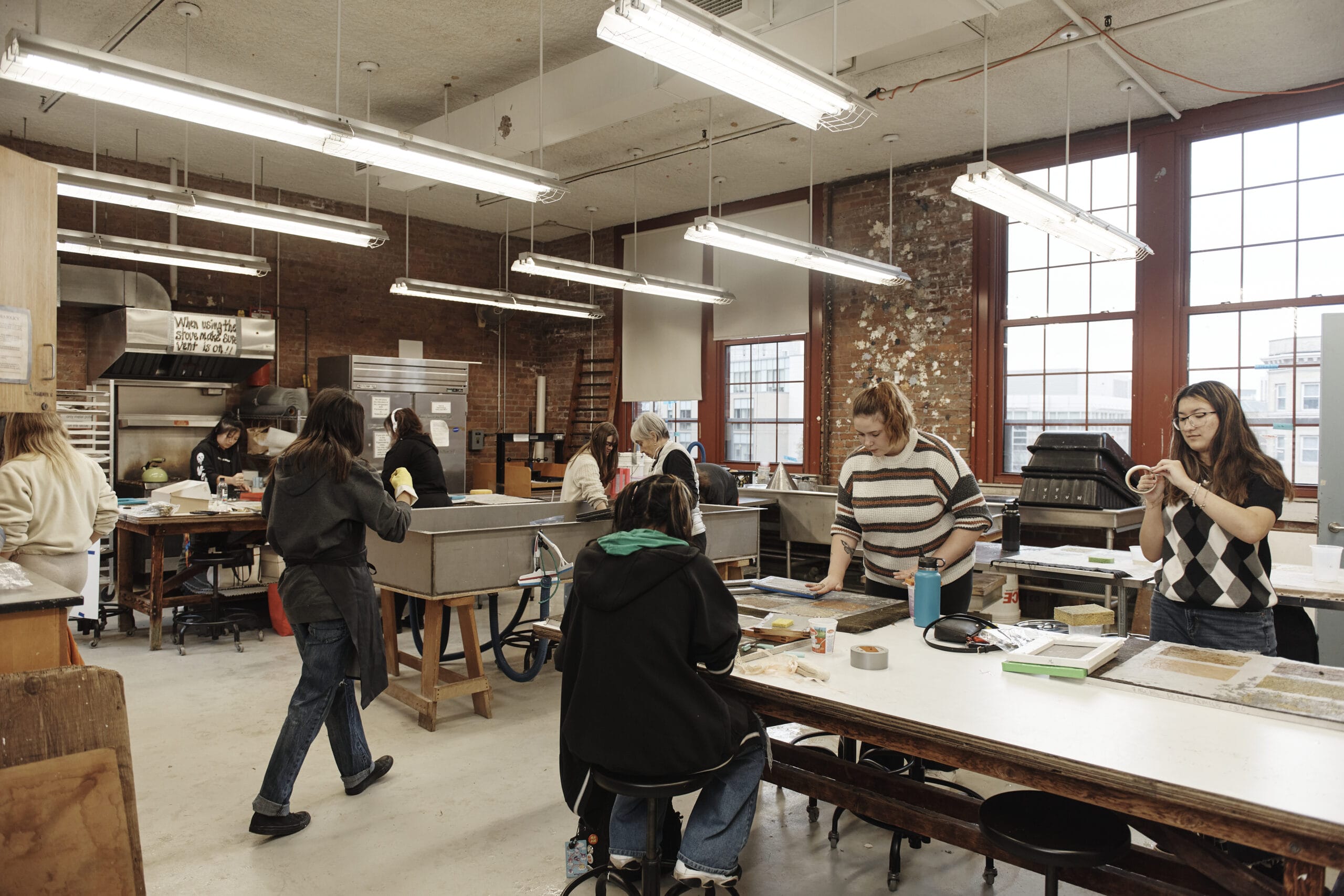 Students standing and working at large tables in the Fibers lab.