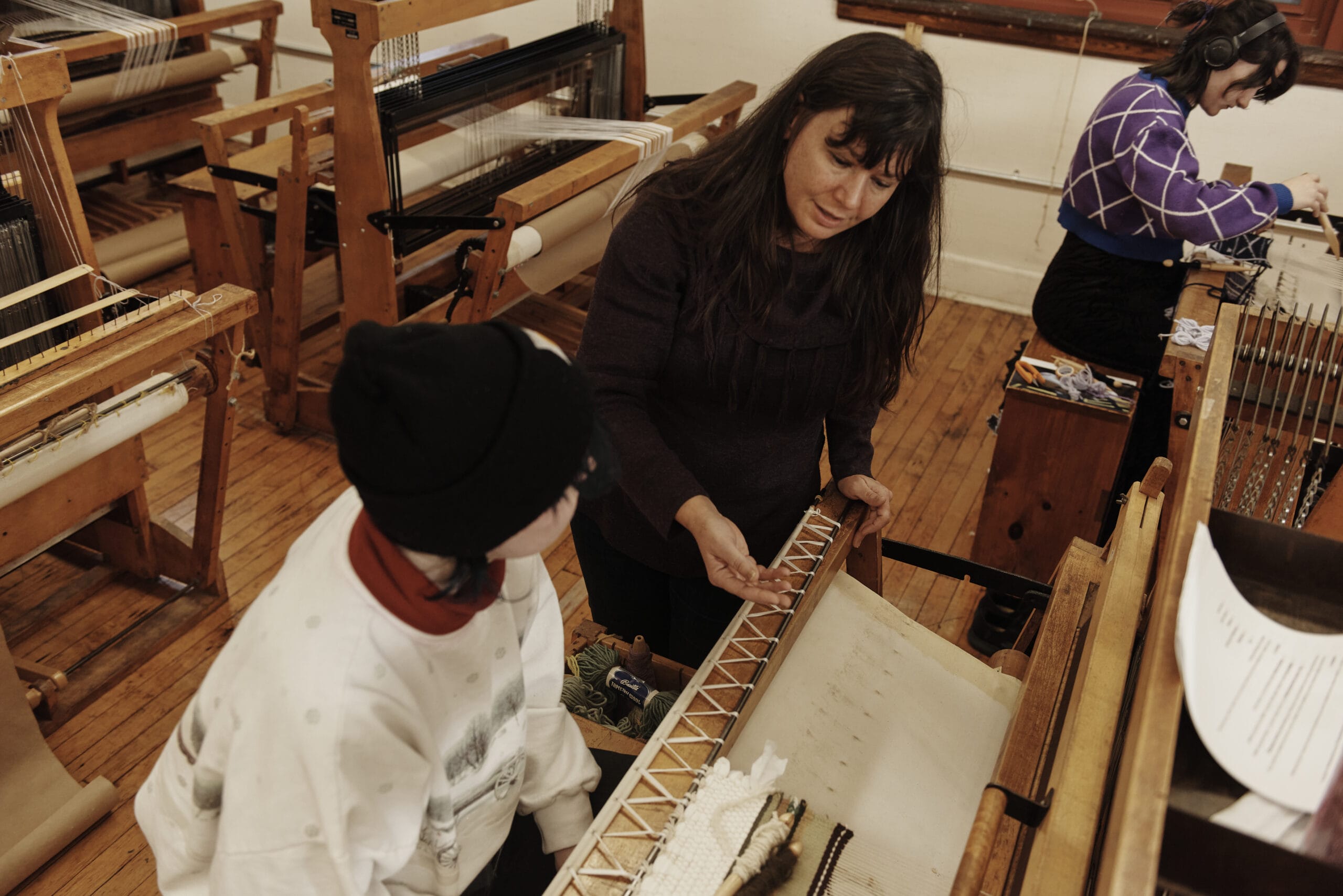 Faculty member Jenine Shereos stands over a student weaving