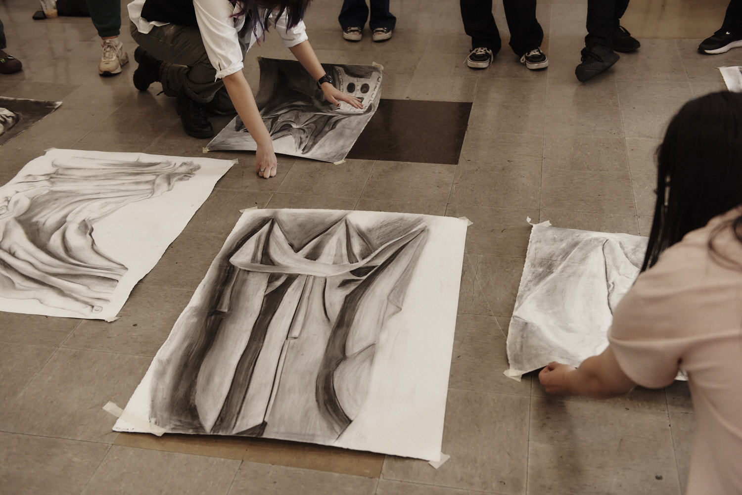 Students displaying artwork on the floor