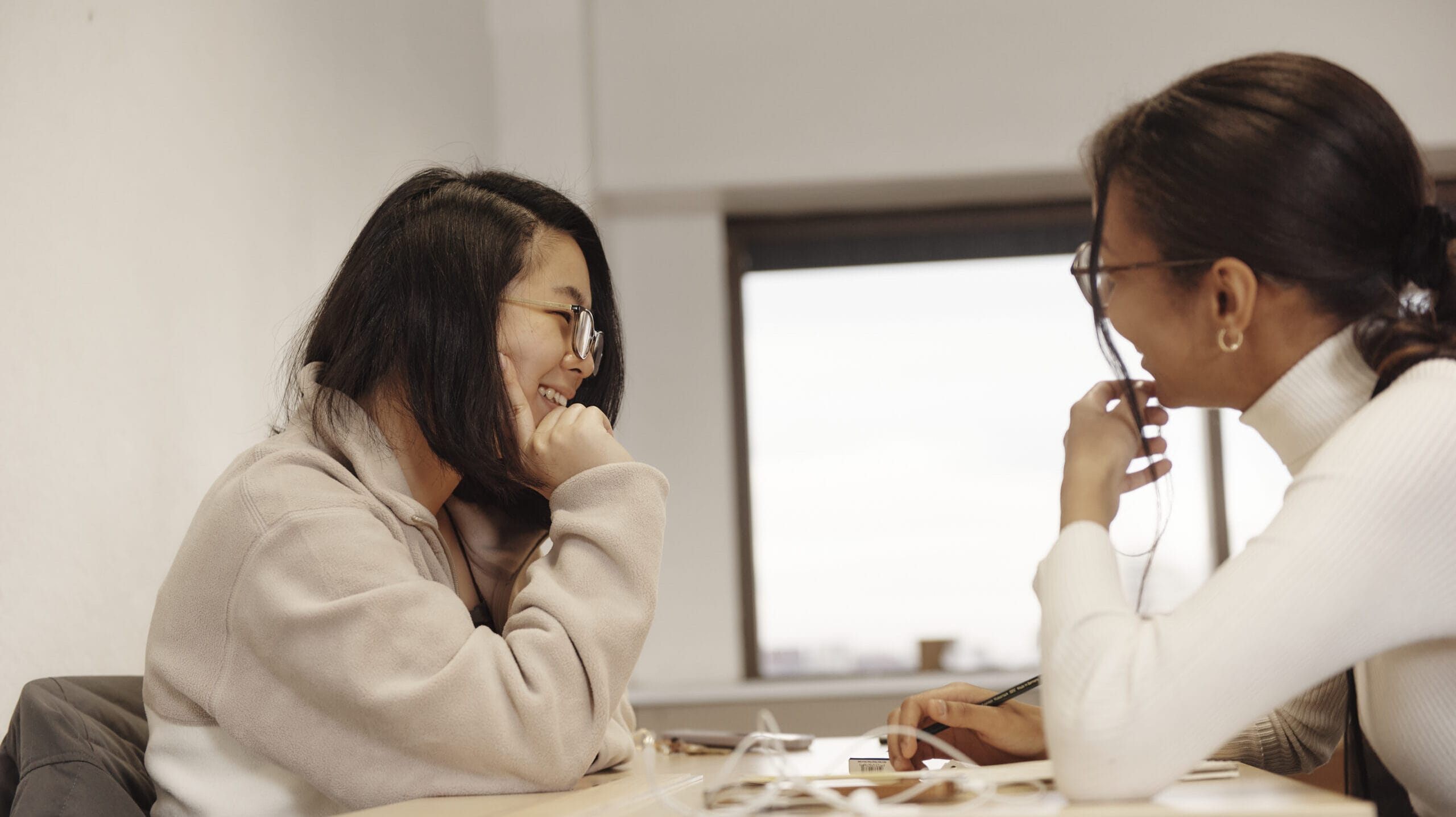 Two students sit across from one another at a table.