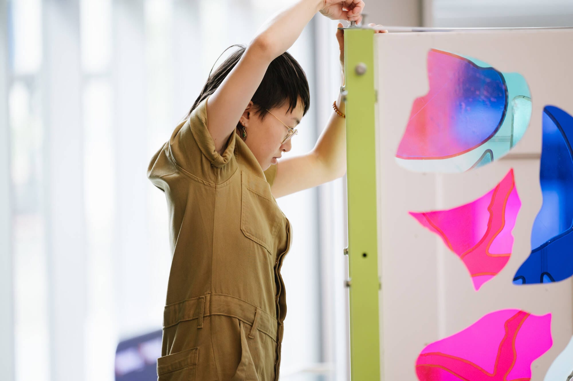 A woman installing a colorful piece of artwork