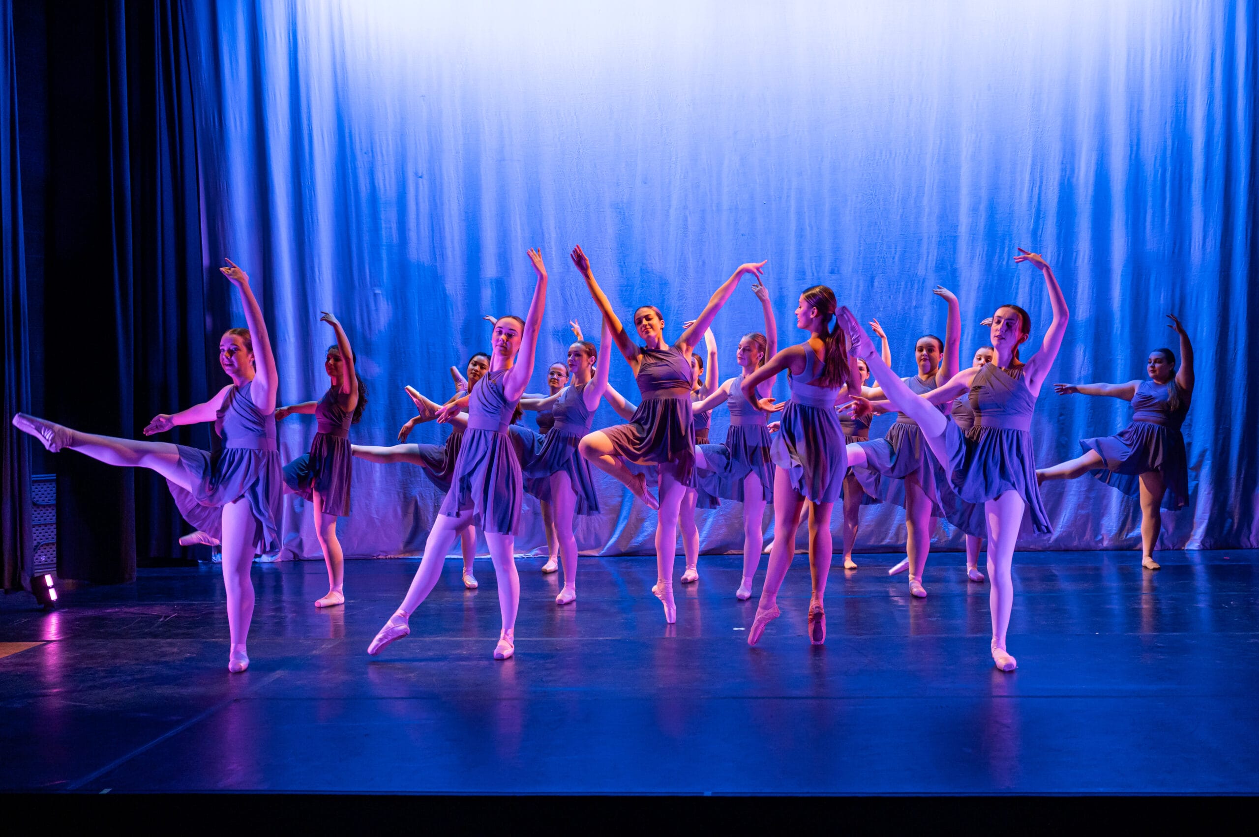 Ballet students perform on a blue-lit stage