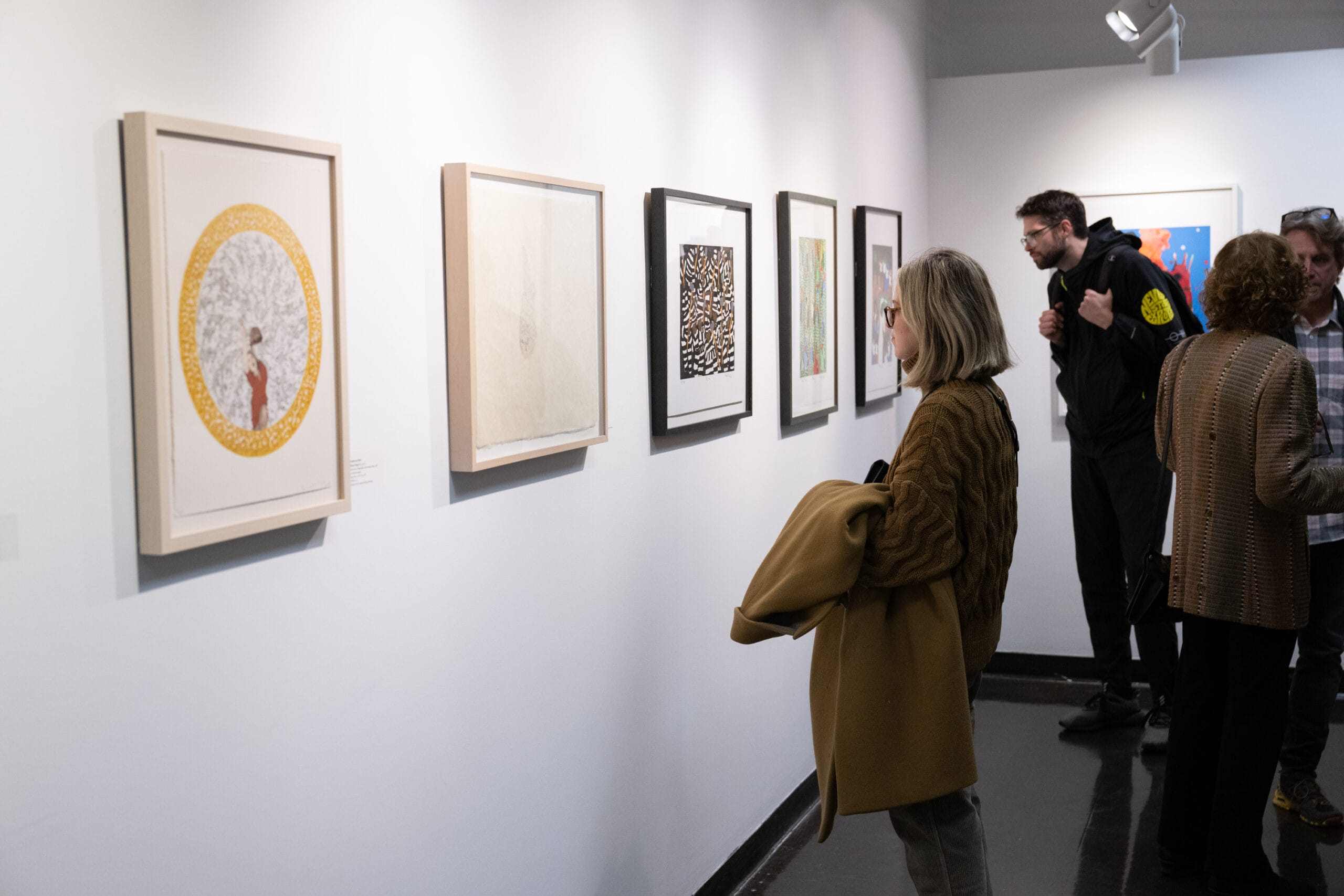 Woman looking at artwork on a white wall.