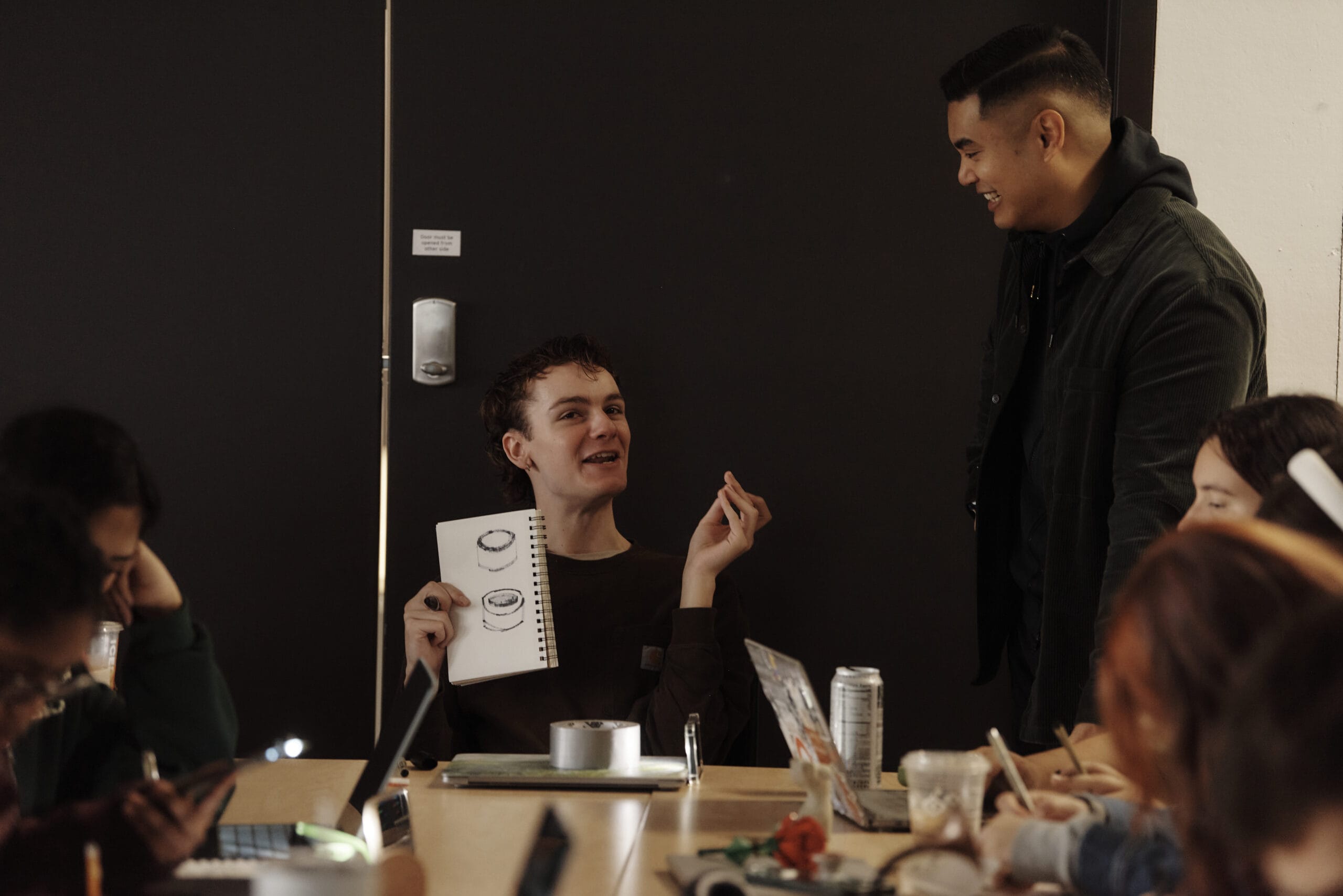 A student talks to his professor and the teacher leans in and smiles.
