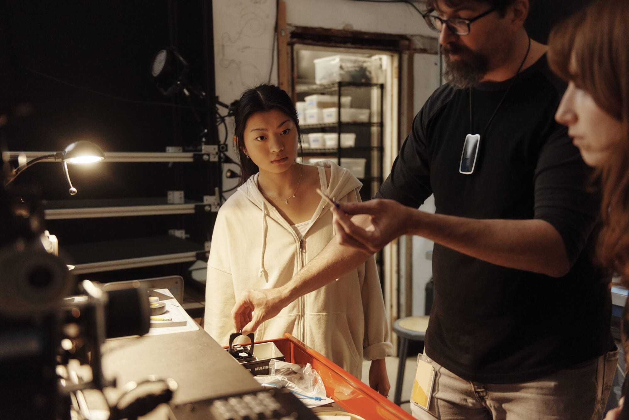 A student watches as a professor shows how to use animation film equipment