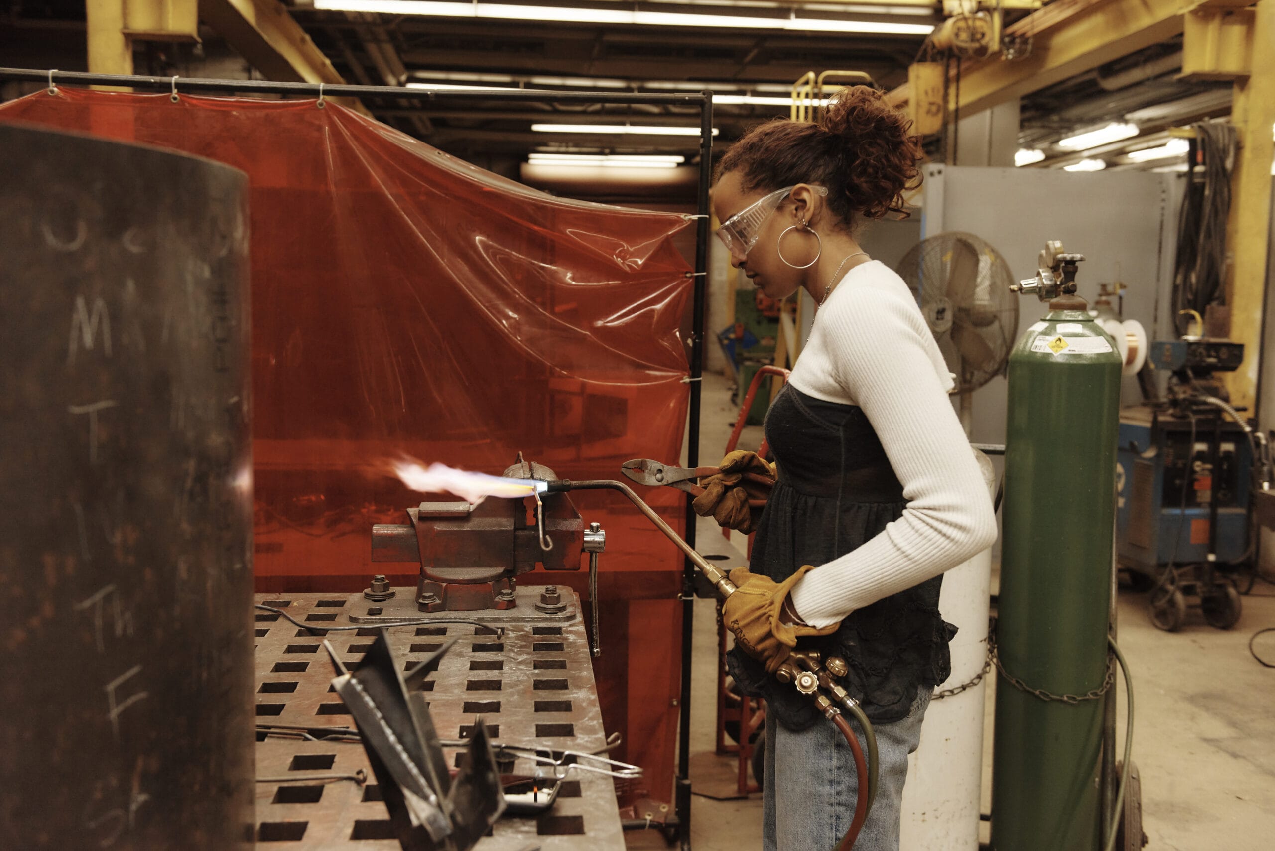 A student holds a blow torch in the large metals studio.