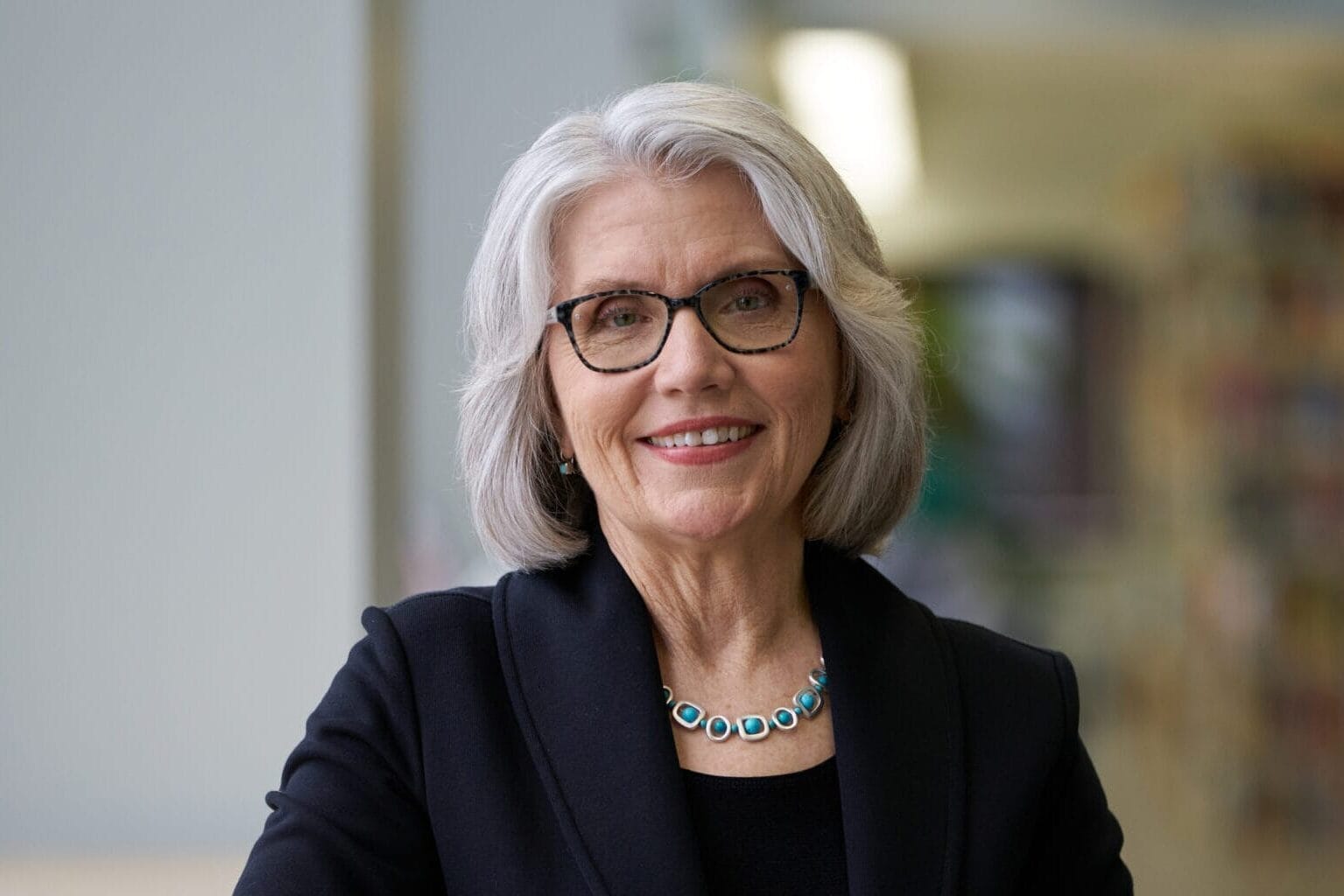 President Mary Grant stands in the library, with her arm on a high-top table.
