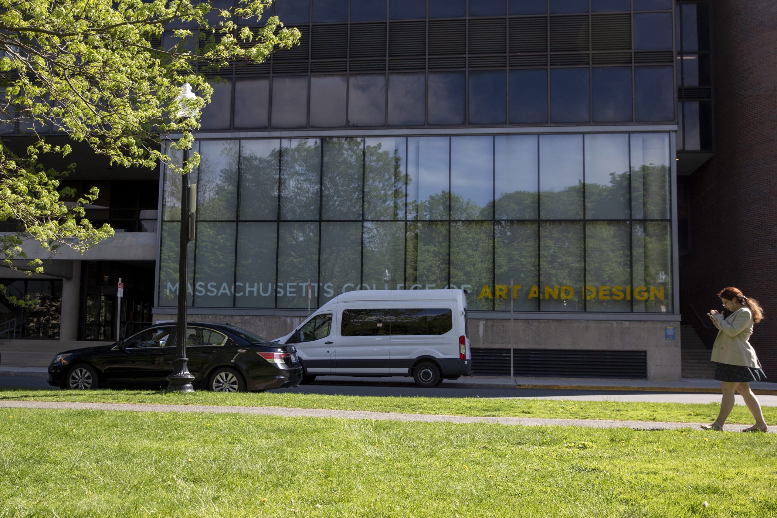 A shuttle bus parked in front of the a building at Massachusetts College of Art and Design.