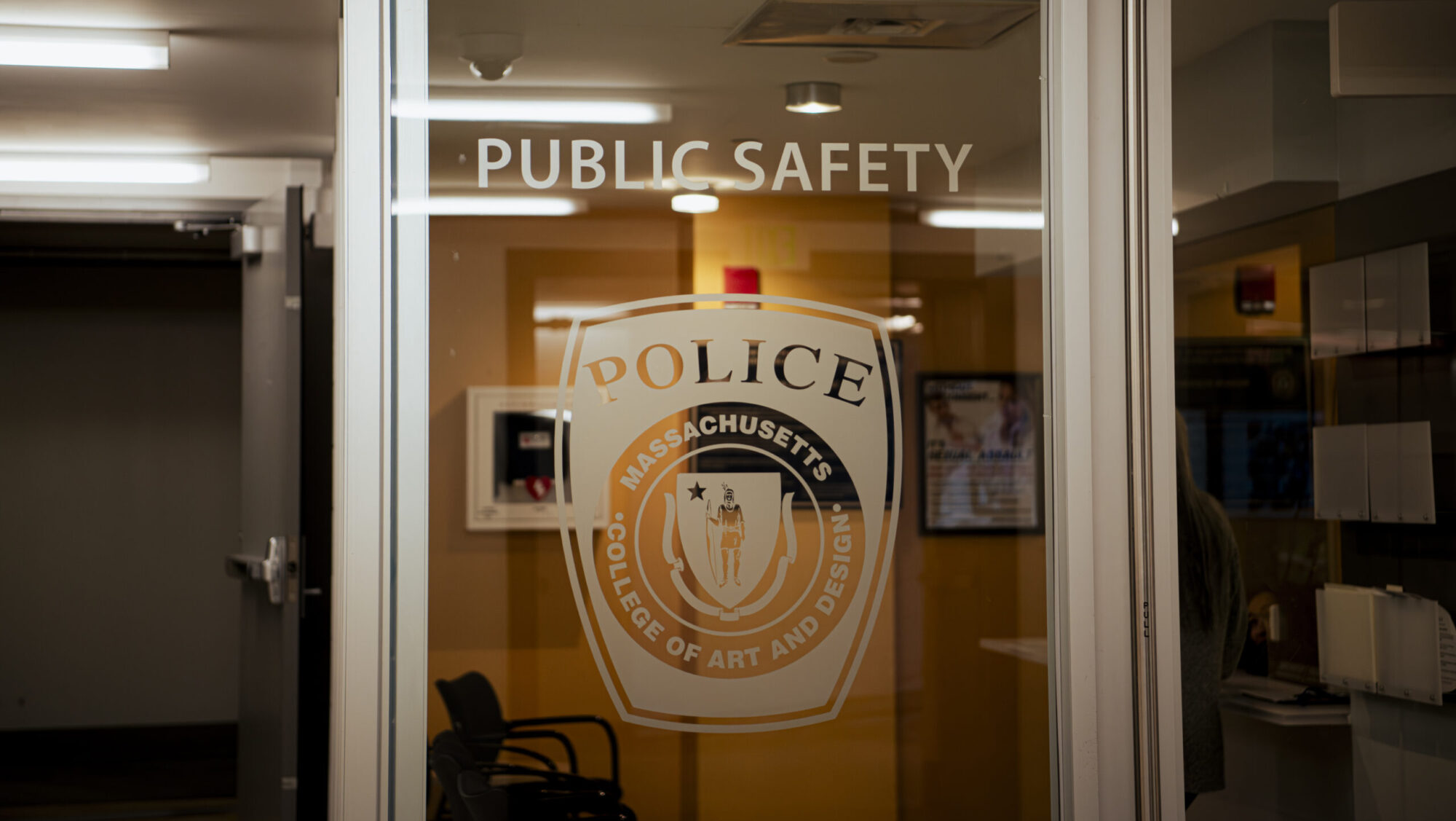 Photo of a glass door with the following words etched into it: PUBLIC SAFETY, Police, Massachusetts College of Art and Design