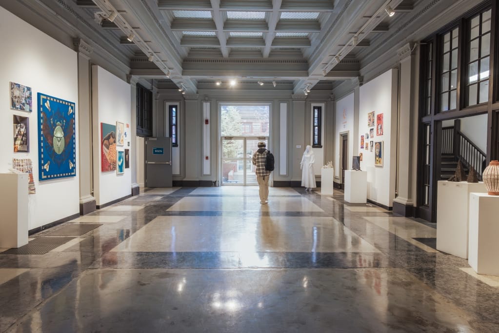 Photo of person walking through a hallway art gallery.